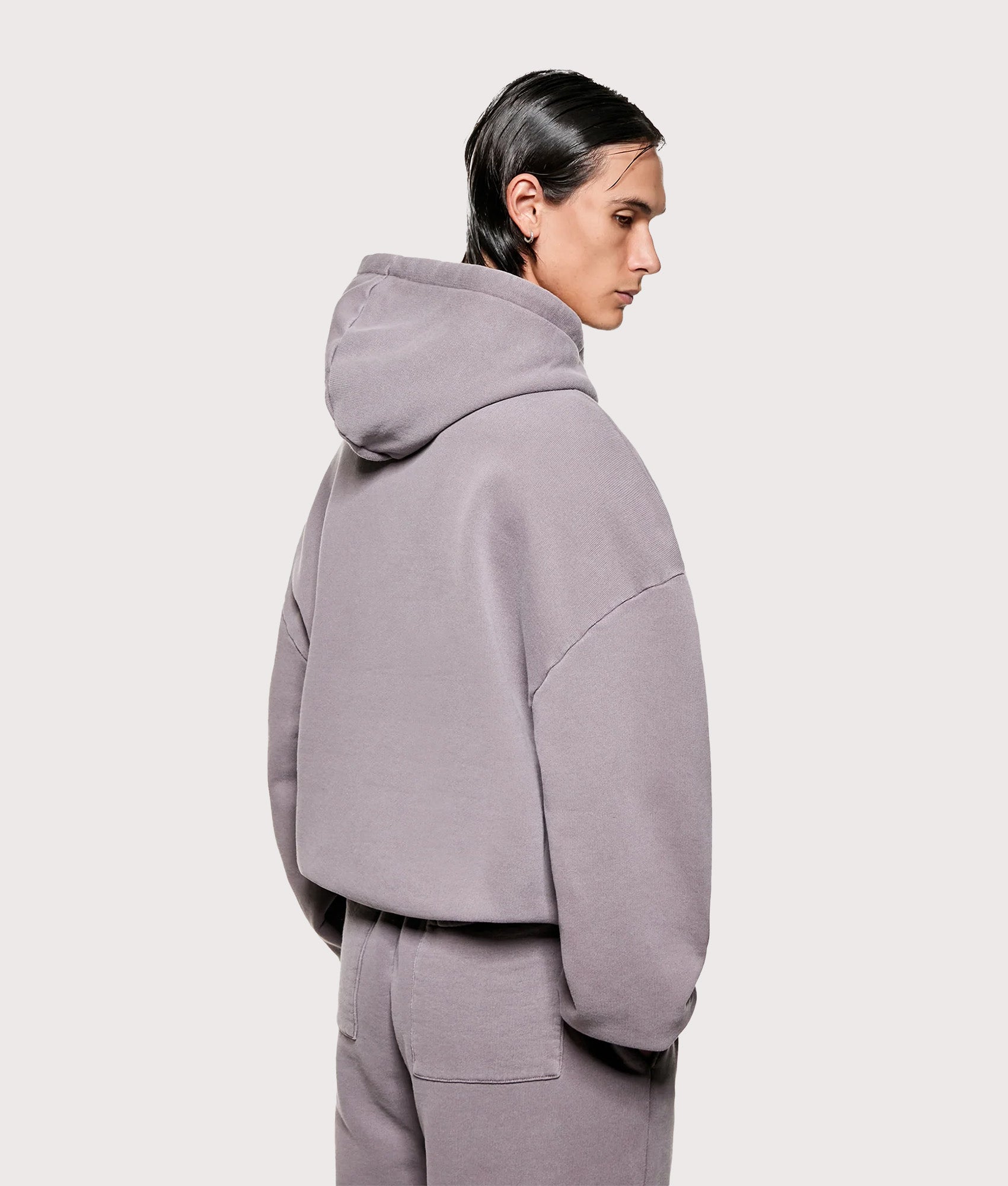 MKI MIYUKI ZOKU Uniform Hoodie in Pigment Raisin at EQVVS Menswear. Angled model back shot.