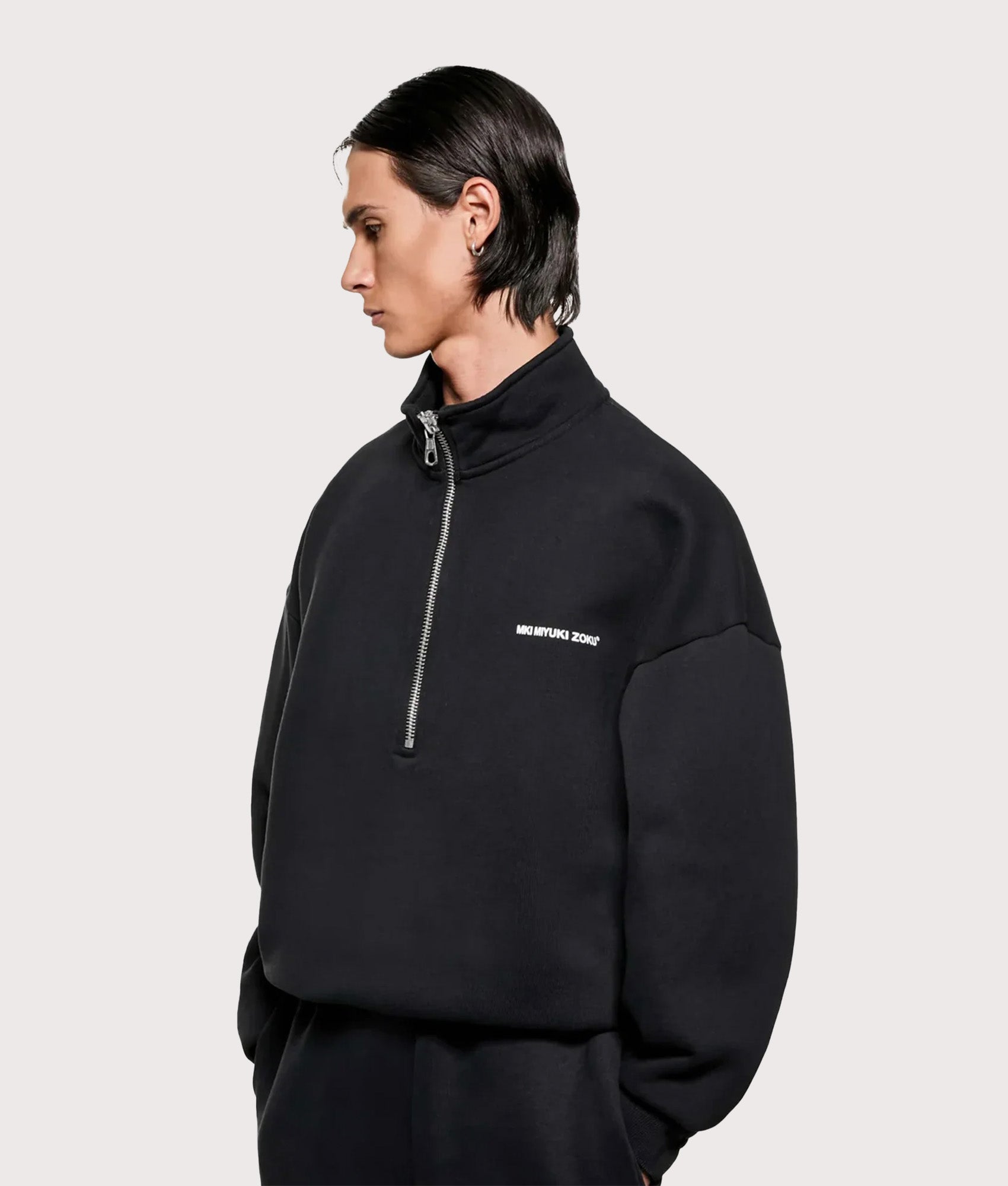 MKI MIYUKI ZOKU Oversized Fit MKI Uniform Quarter Zip in Black at EQVVS Menswear. Angled model front shot.