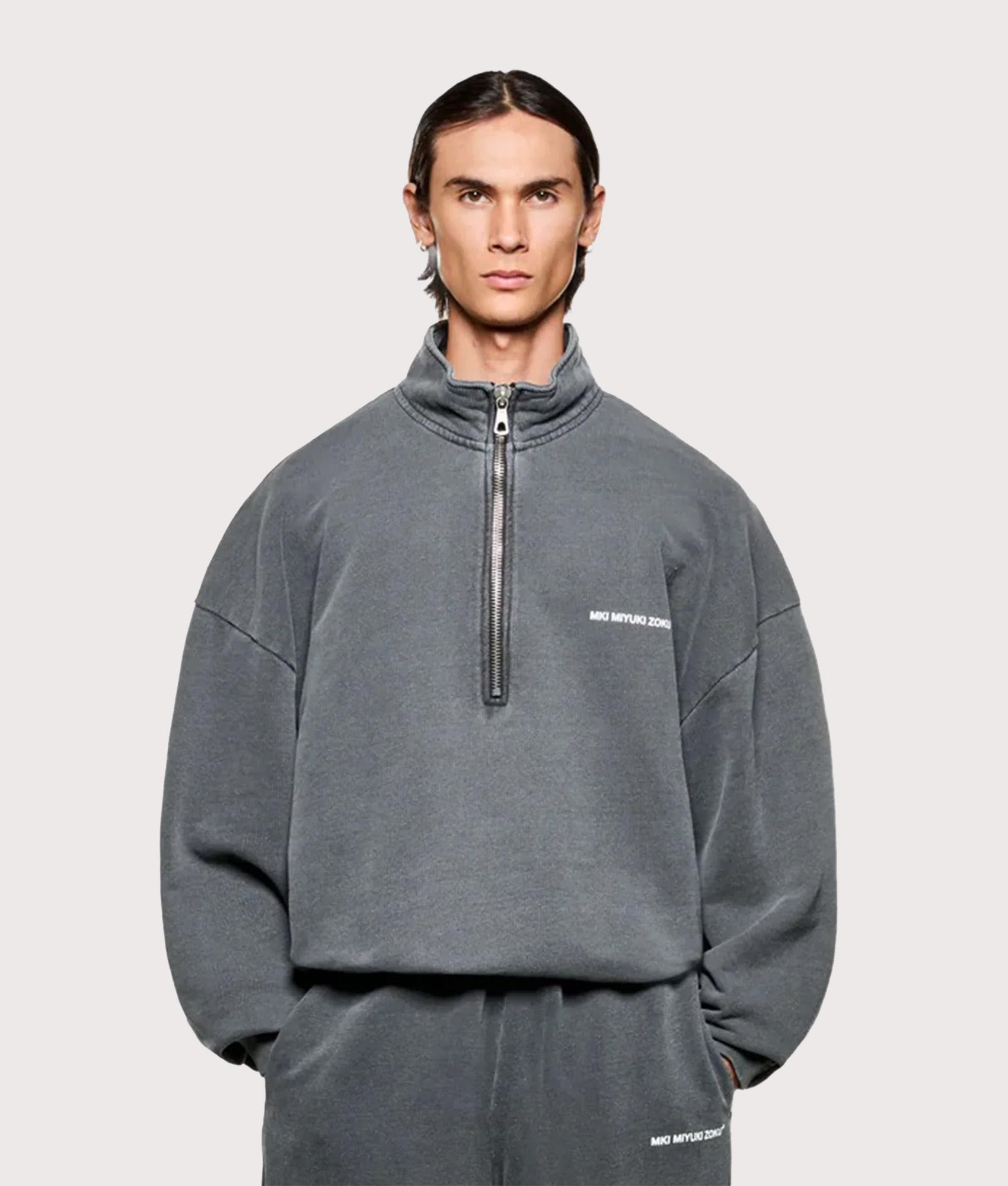MKI MIYUKI ZOKU Oversized Uniform Quarter Zip Sweatshirt in Pigment Black at EQVVS Menswear. Model front shot.