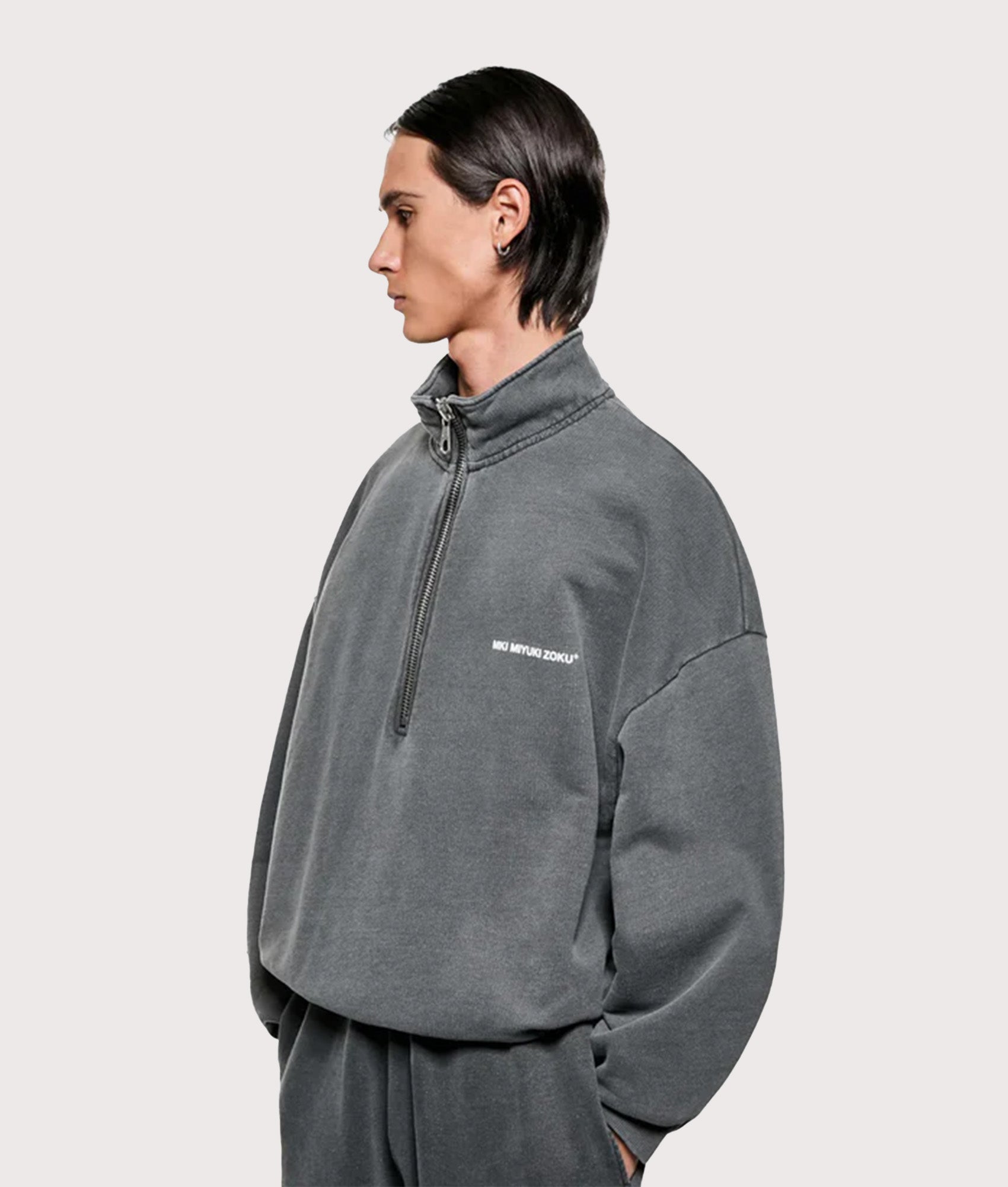 MKI MIYUKI ZOKU Oversized Uniform Quarter Zip Sweatshirt in Pigment Black at EQVVS Menswear. Angled model front shot.
