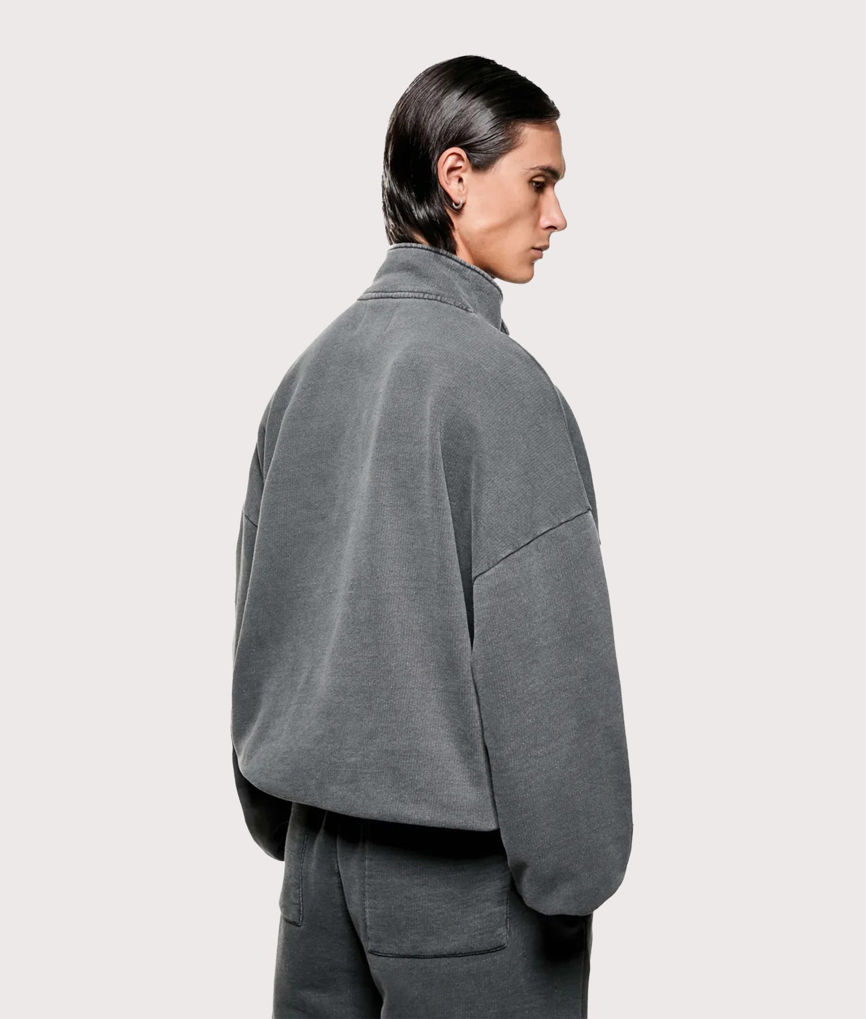 MKI MIYUKI ZOKU Oversized Uniform Quarter Zip Sweatshirt in Pigment Black at EQVVS Menswear. Angled model back shot.