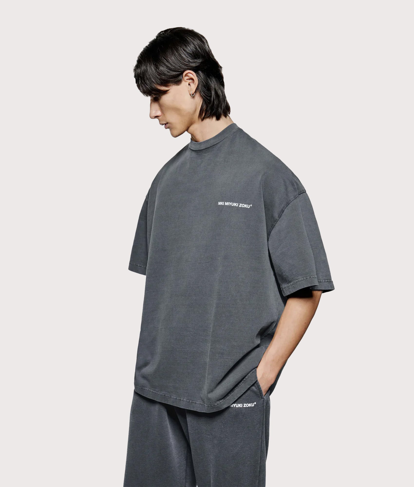 MKI MIYUKI ZOKU Oversized Uniform T-Shirt in Pigment Black at EQVVS Menswear. Angled model back shot.