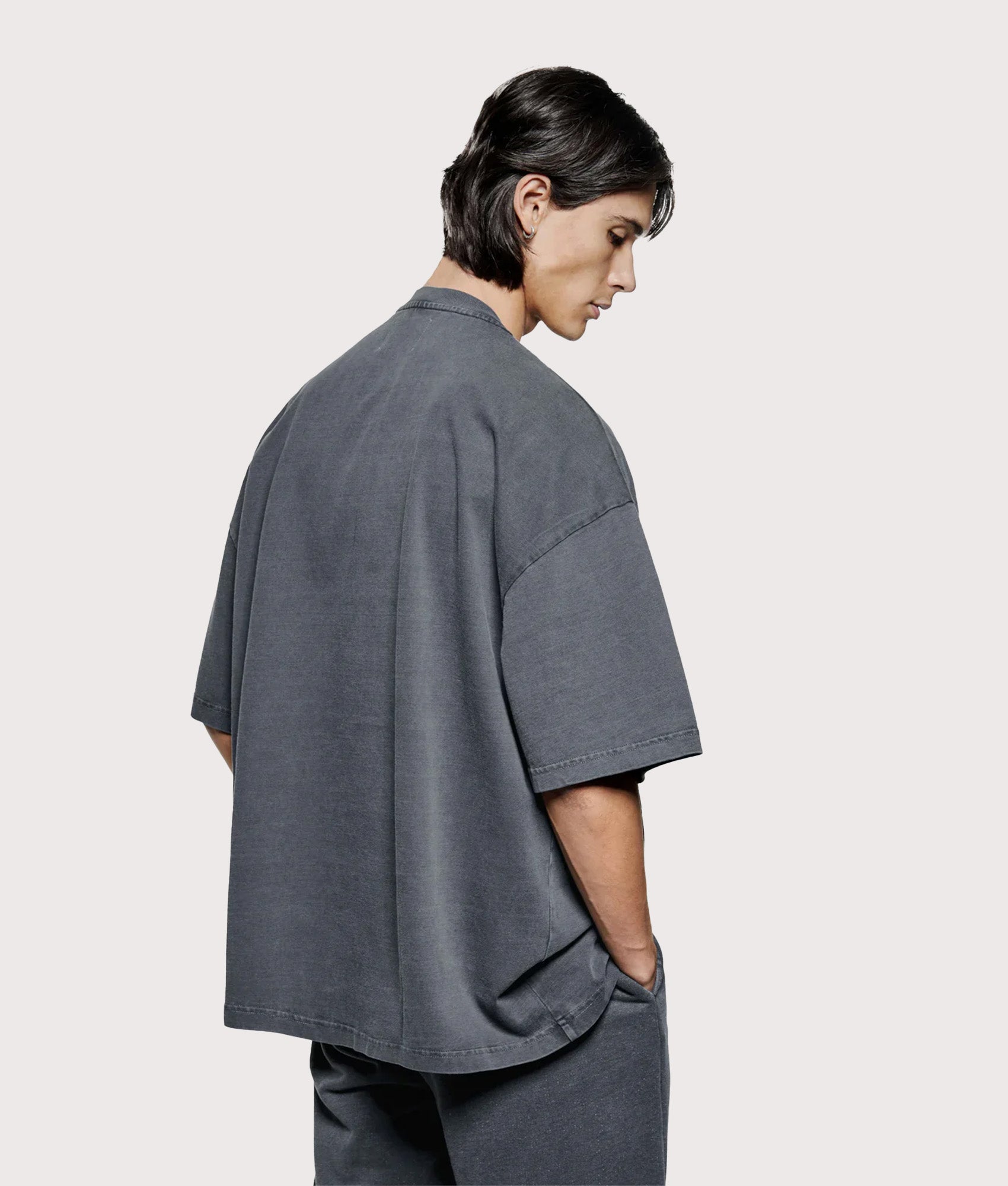 MKI MIYUKI ZOKU Oversized Uniform T-Shirt in Pigment Black at EQVVS Menswear. Angled model back shot.