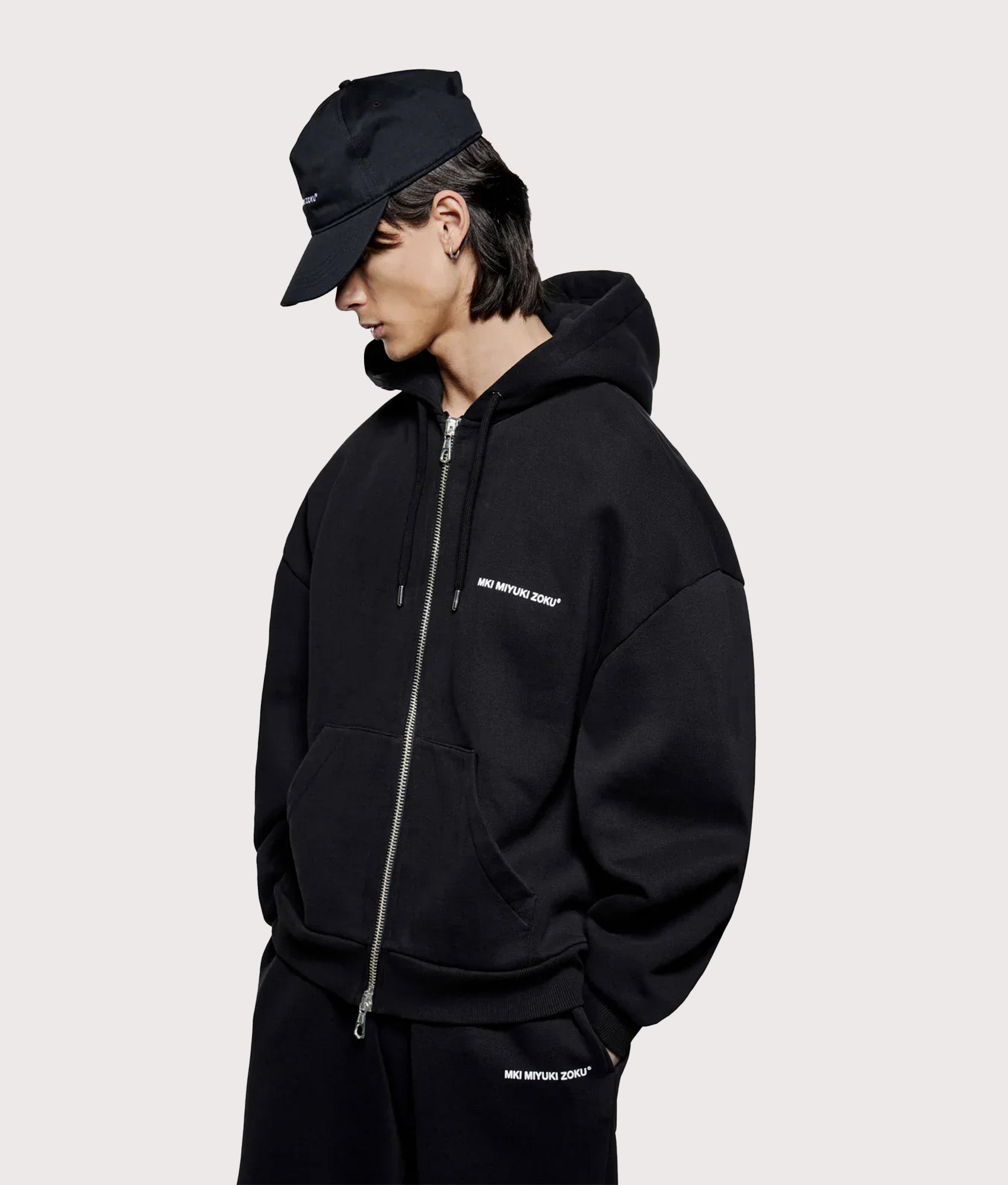 MKI MIYUKI ZOKU Oversized Uniform zip through hoodie in Black at EQVVS Menswear. Angled model front shot.
