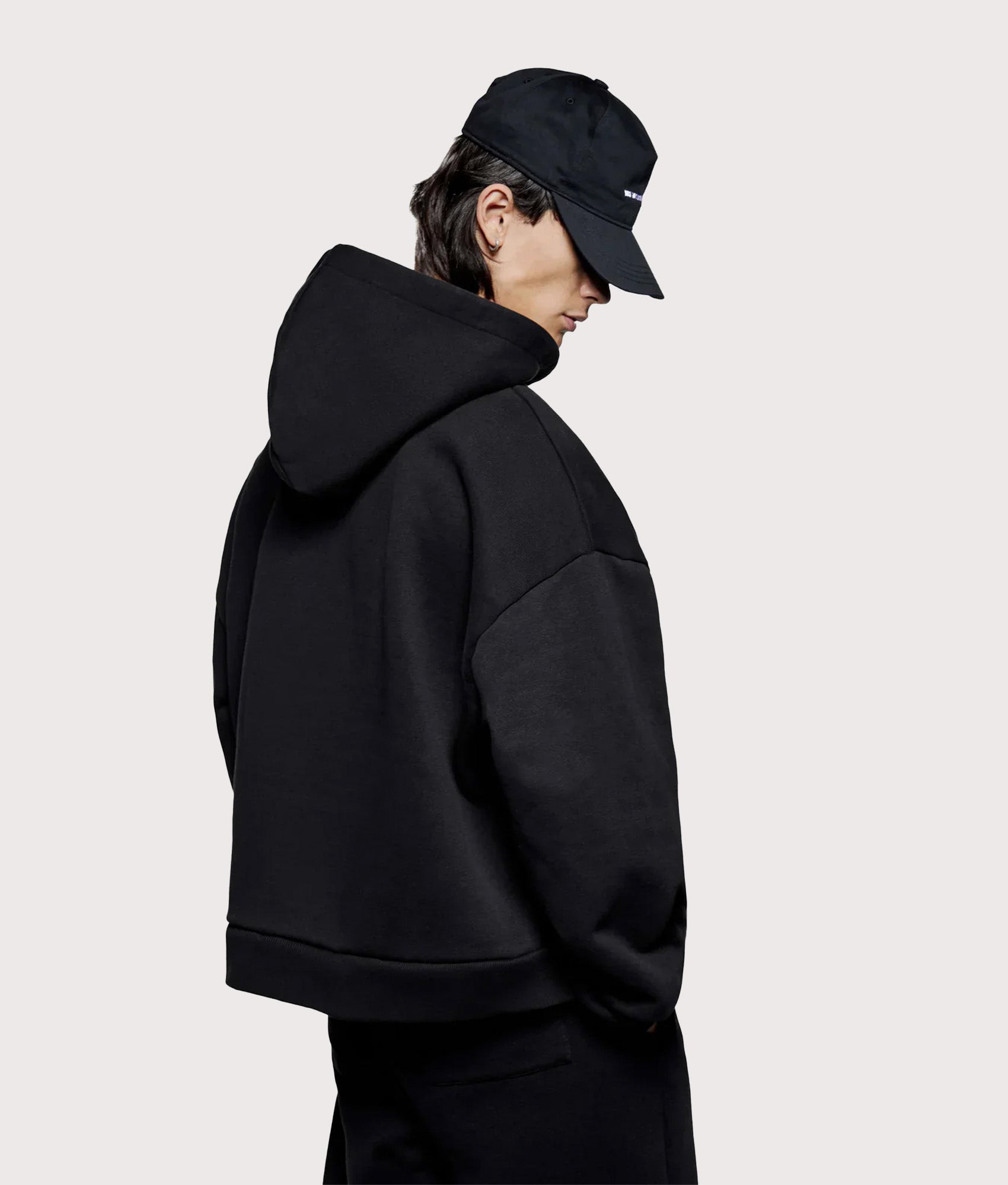 MKI MIYUKI ZOKU Oversized Uniform zip through hoodie in Black at EQVVS Menswear. Angled model back shot.
