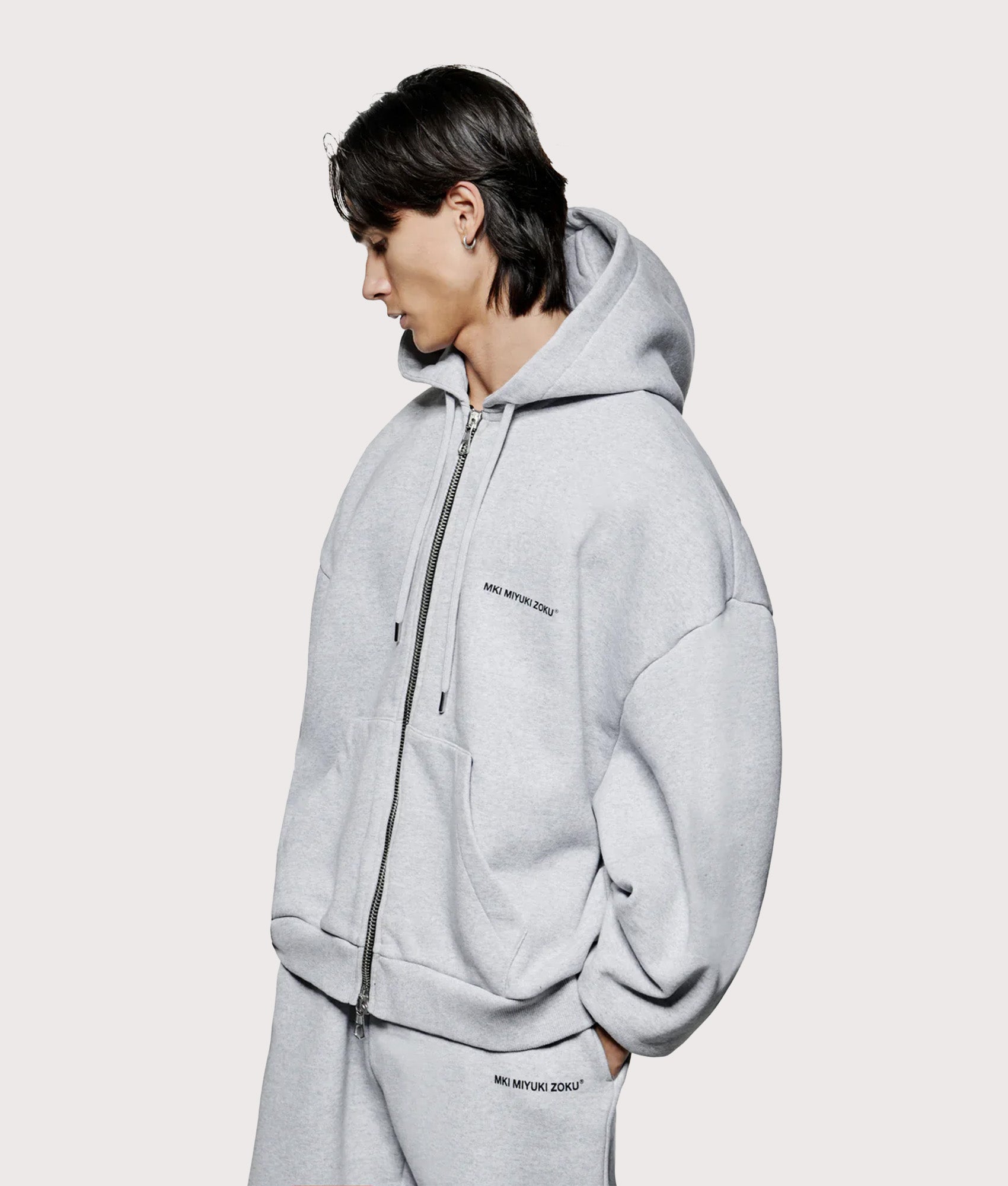 MKI MIYUKI ZOKU Oversized Uniform zip through hoodie in Grey at EQVVS Menswear. Angled model front shot.