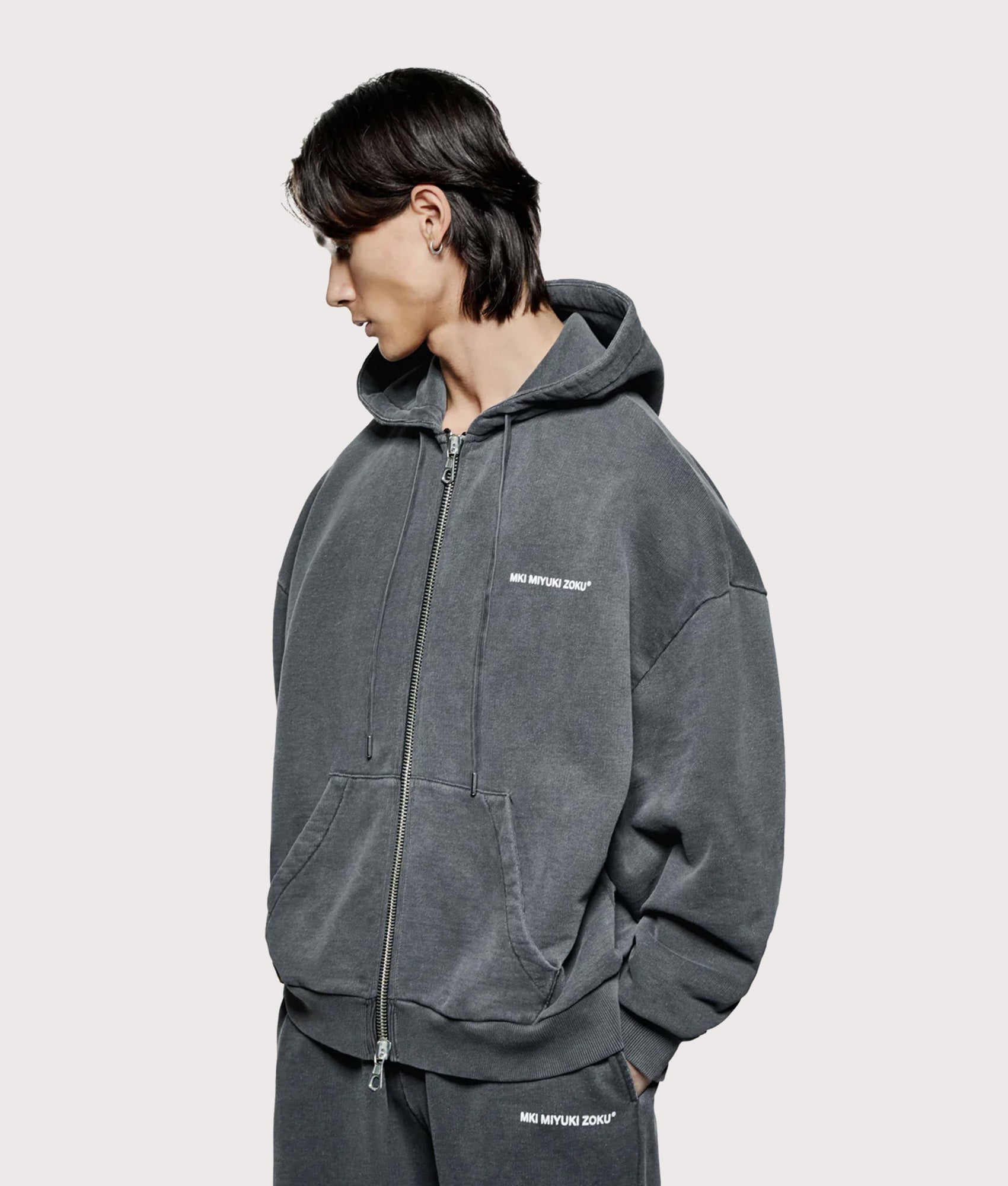 MKI MIYUKI ZOKU Oversized Uniform Zip Through Hoodie in Pigment Black at EQVVS Menswear. Angled model front shot