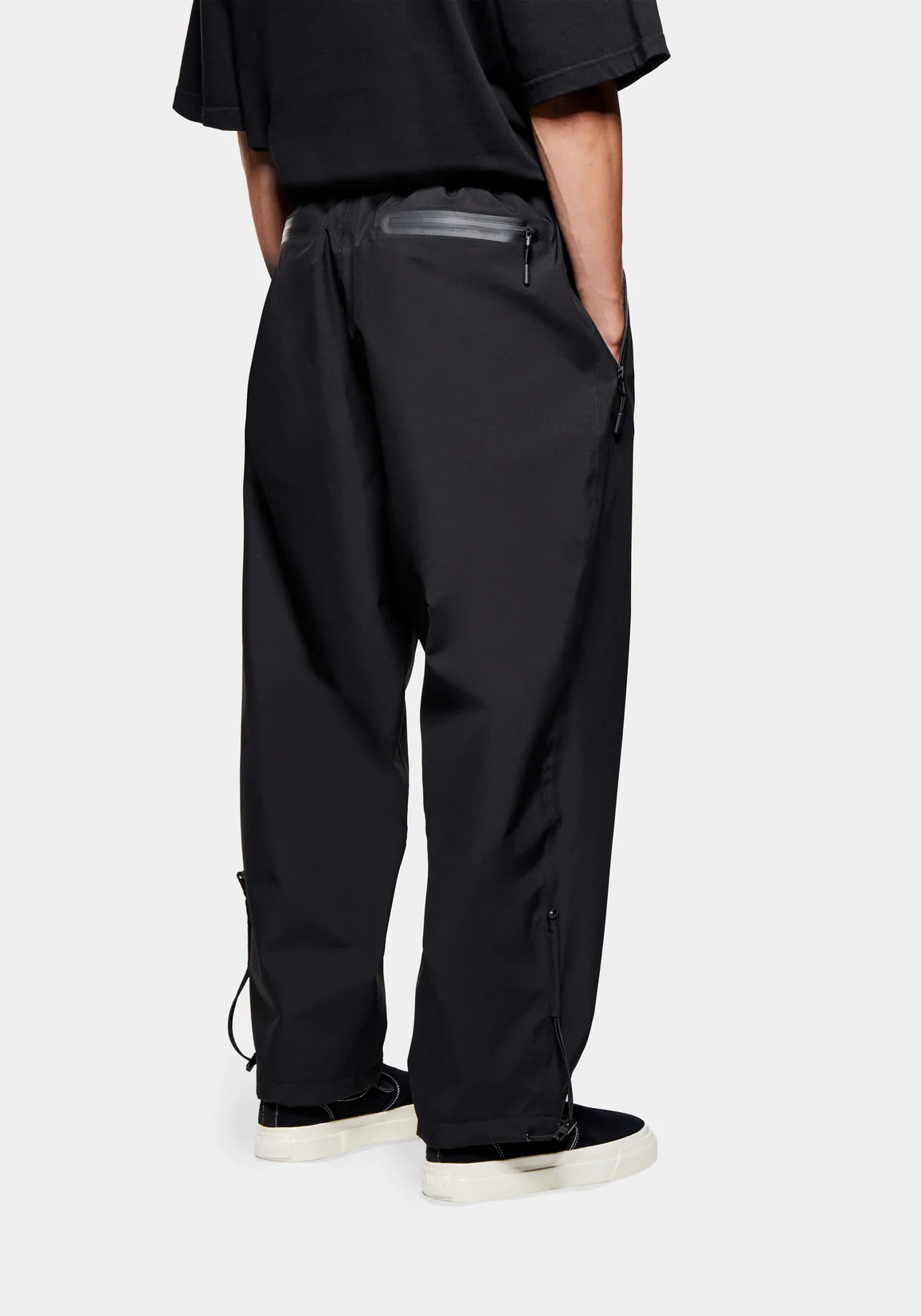 Loose Fit V2 Shell Track Pants in Black by MKI MIYUKI ZOKU at EQVVS. Back Model Shot. 