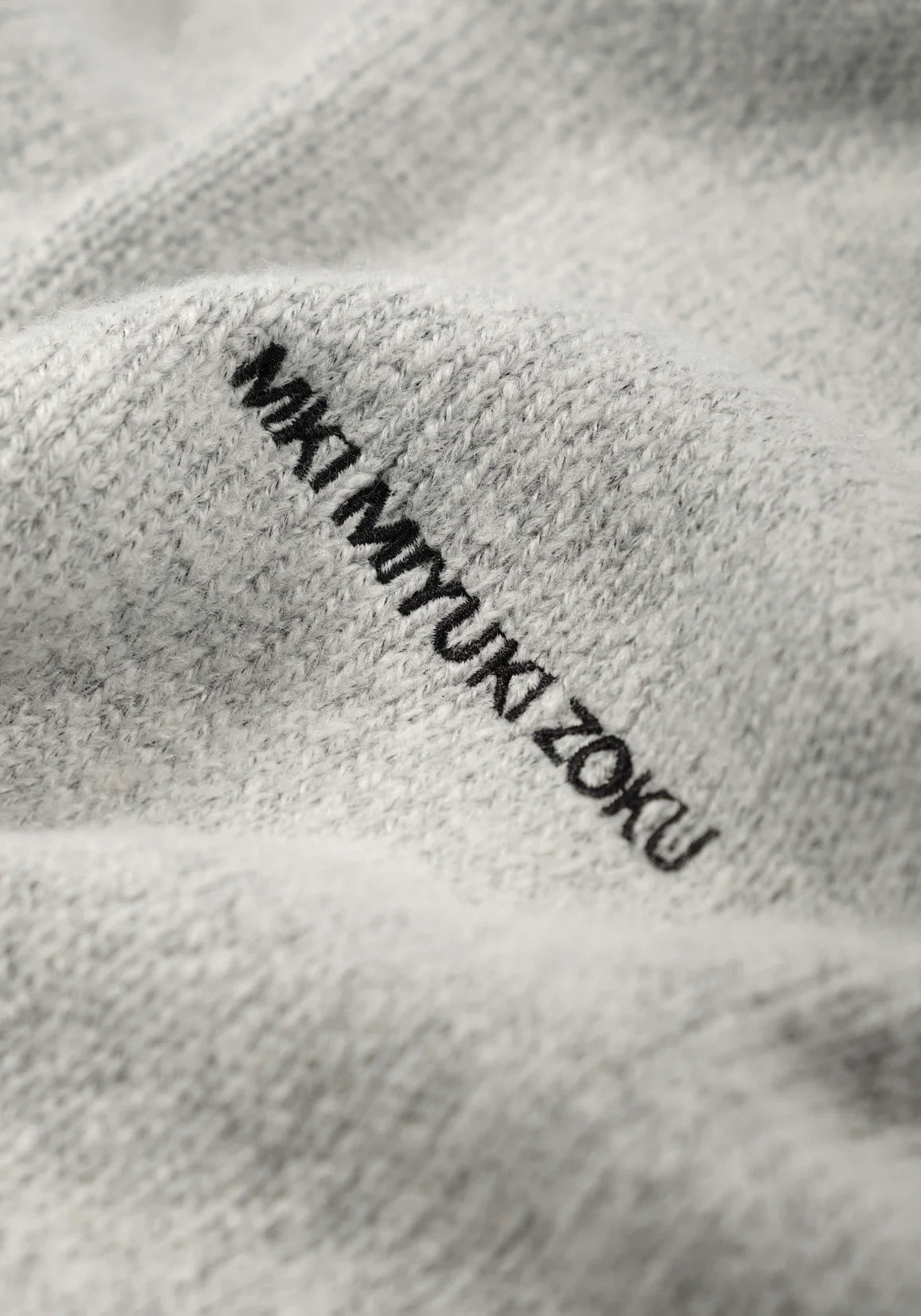 MKI MIYUKI ZOKU Mohair Blend Knit Hoodie in Light Grey at EQVVS Menswear. Detail Logo Shot.