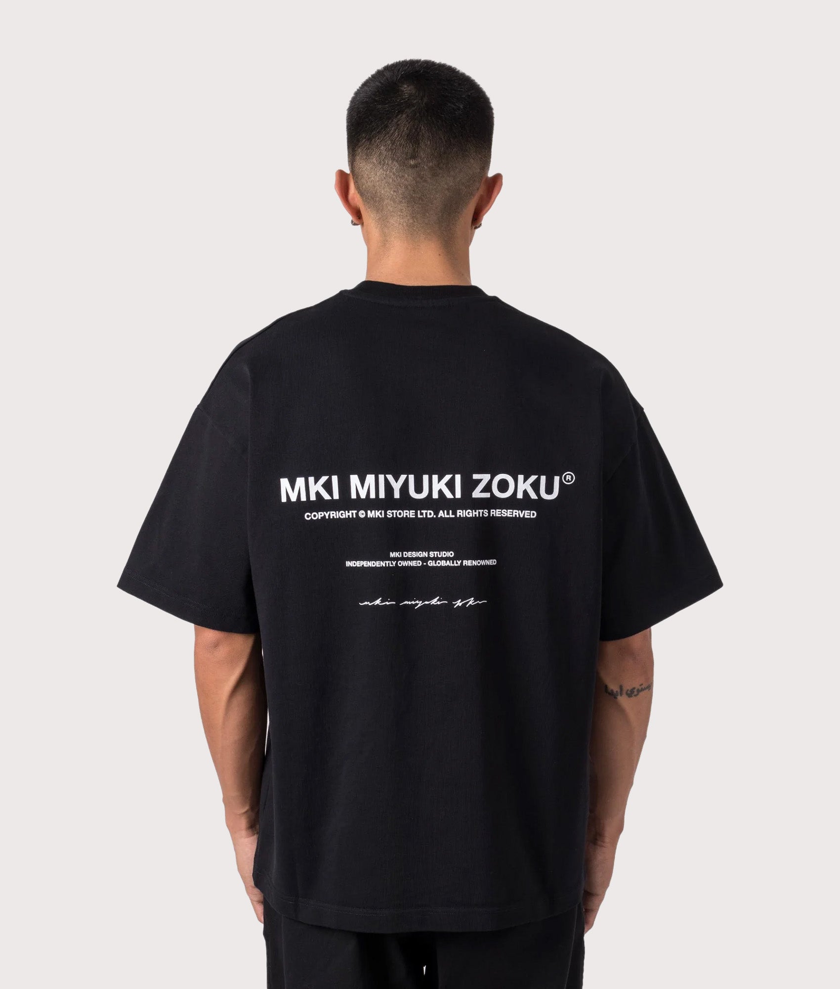 MKI MIYUKI ZOKU Oversized Fit Design Studio T-Shirt in Black at EQVVS Menswear. Model back shot.