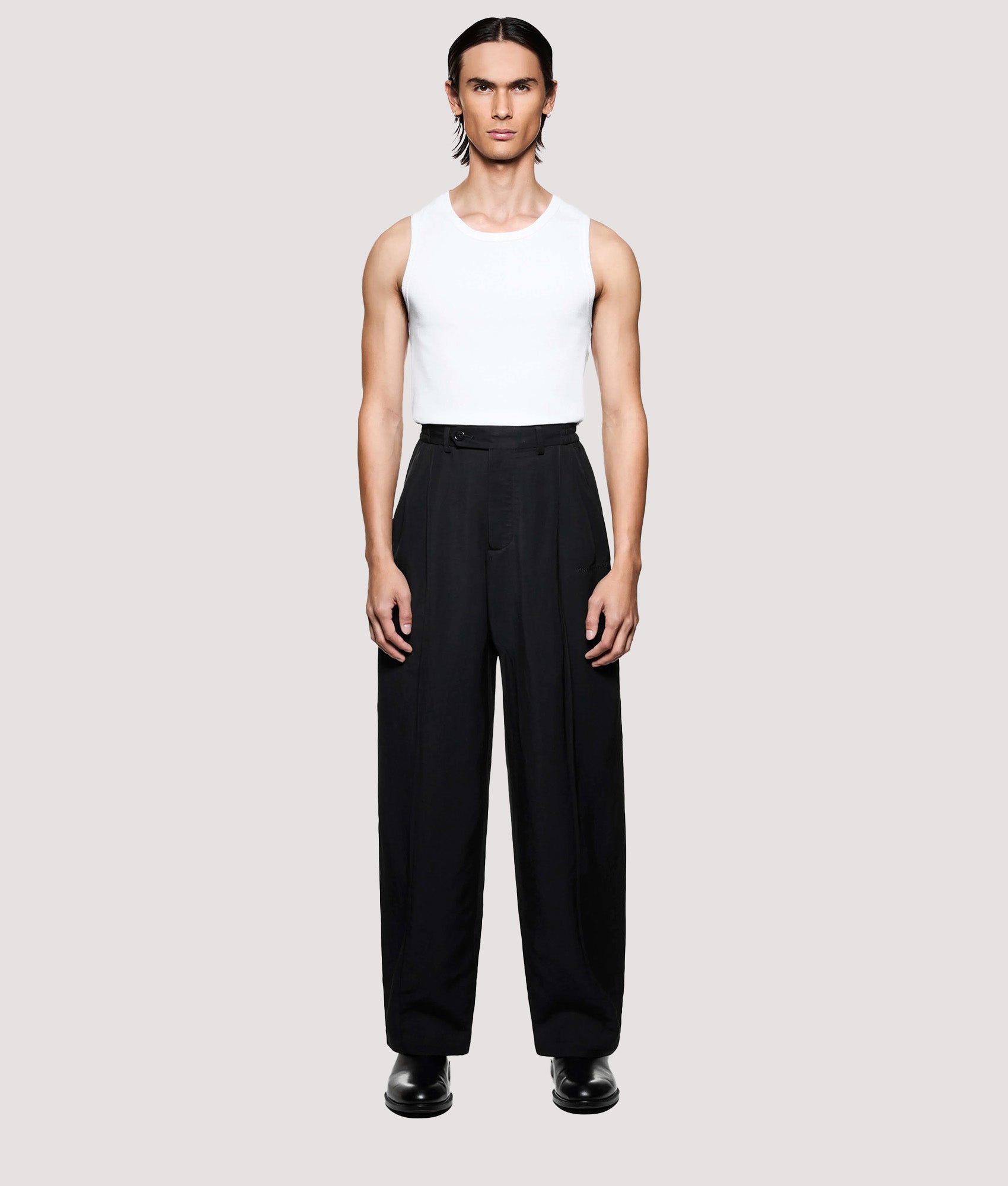 MKI MIYUKI ZOKU Pleated Suit Pants in Black at EQVVS Menswear. Model front shot.