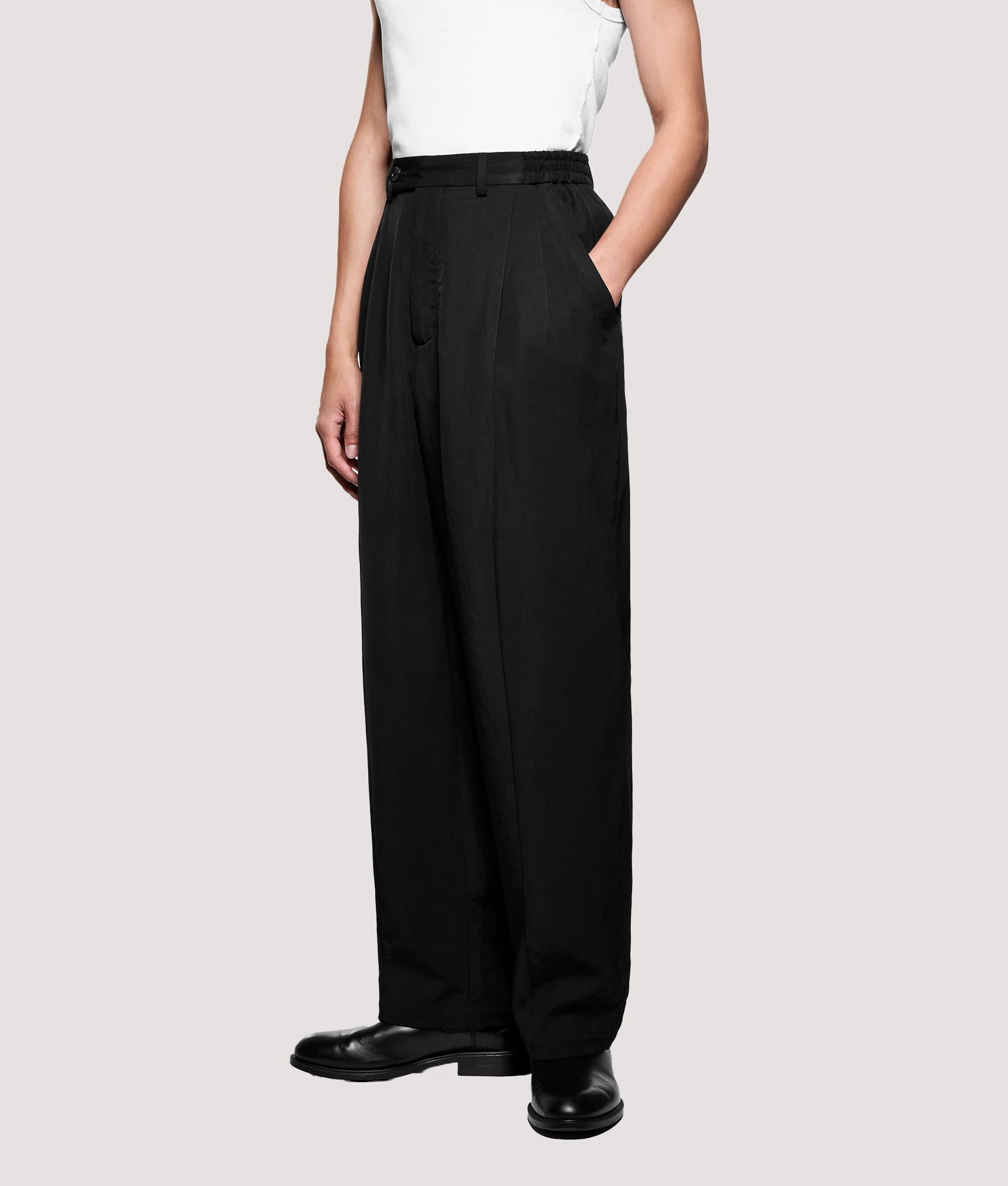 MKI MIYUKI ZOKU Pleated Suit Pants in Black at EQVVS Menswear. Model angled front shot.