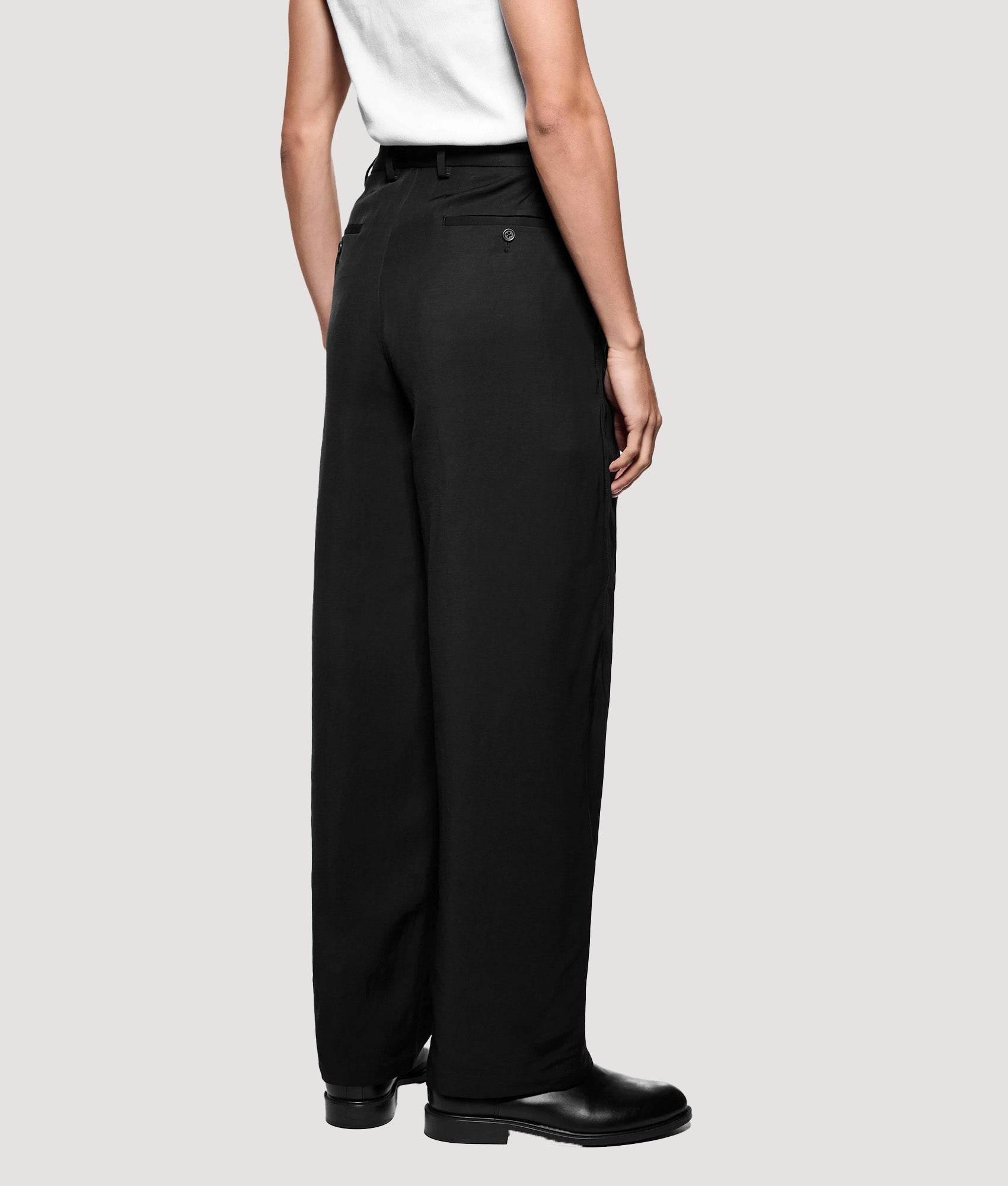 MKI MIYUKI ZOKU Pleated Suit Pants in Black at EQVVS Menswear. Angled model back shot.