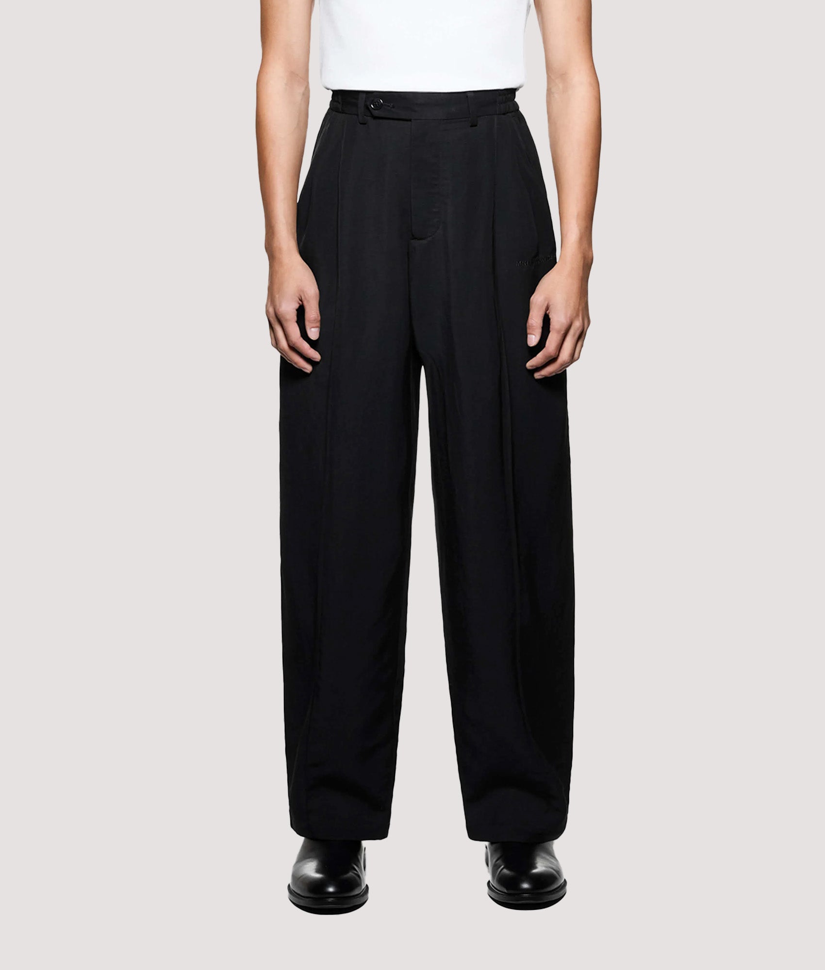 MKI MIYUKI ZOKU Pleated Suit Pants in Black at EQVVS Menswear. Model front shot. 