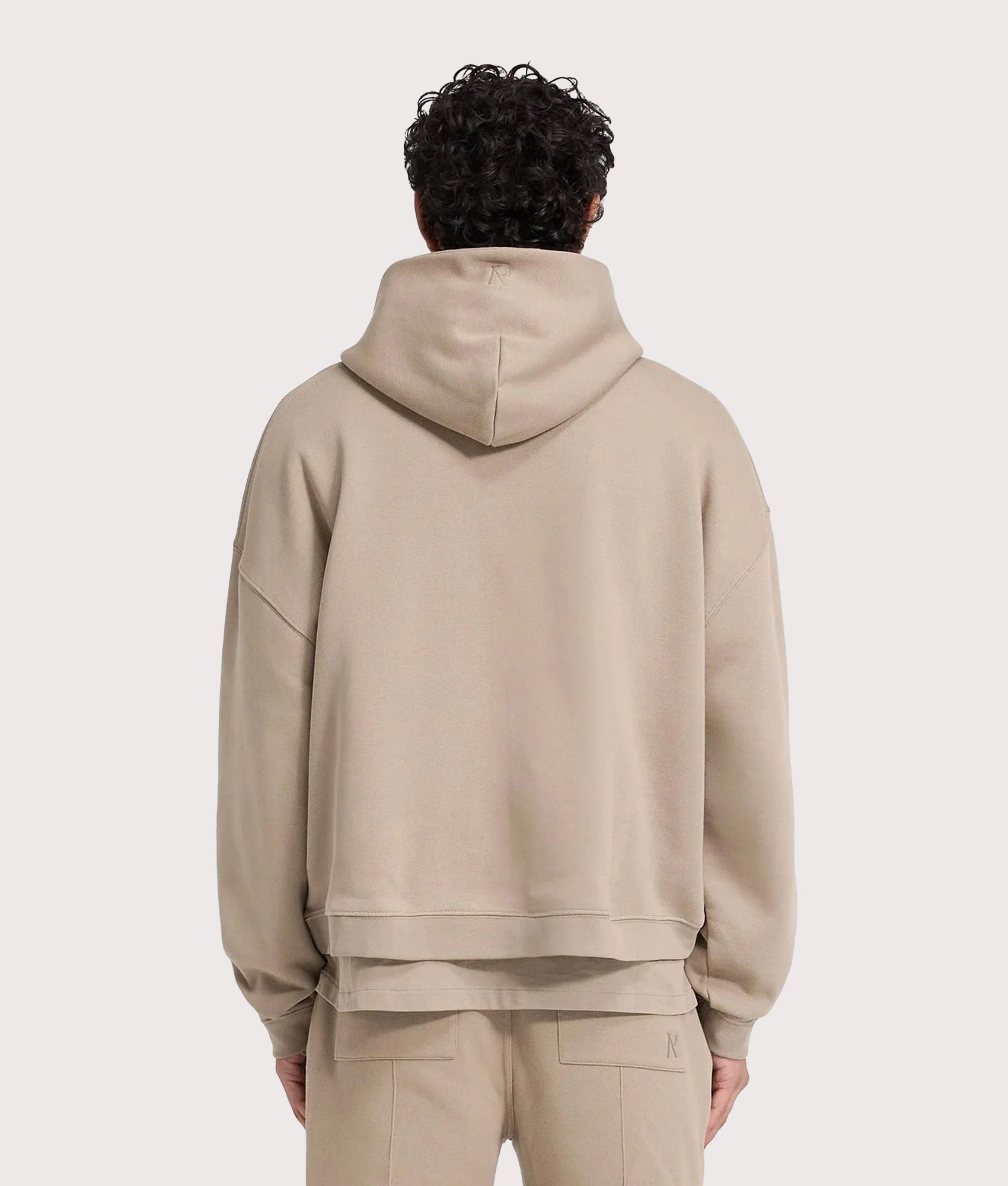 REPRESENT Oversized Initial Boxy Hoodie in Dune at EQVVS Menswear. Model back shot.