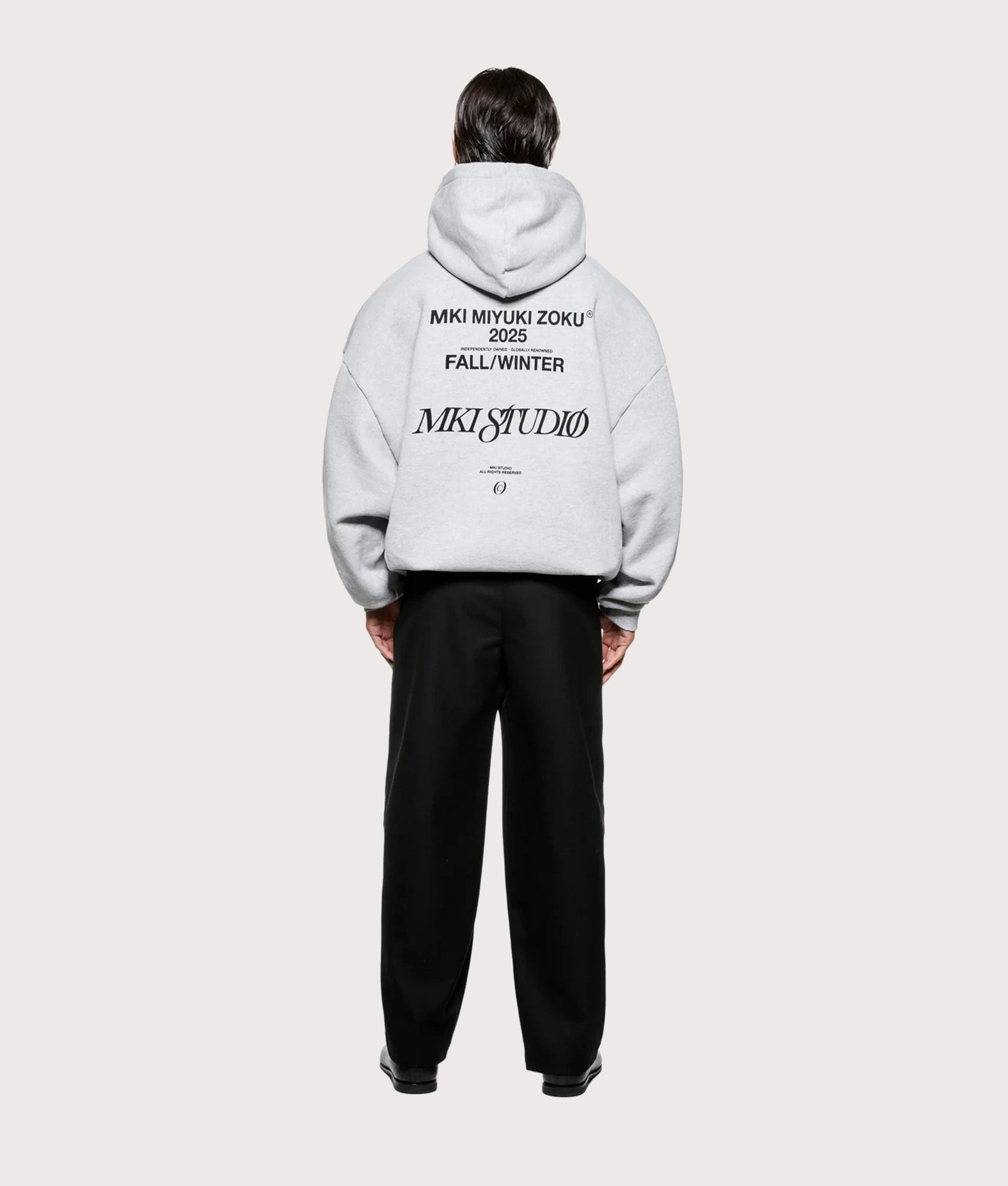 MKI MIYUKI ZOKU Script hoodie in Grey at EQVVS Menswear. Model full back shot.