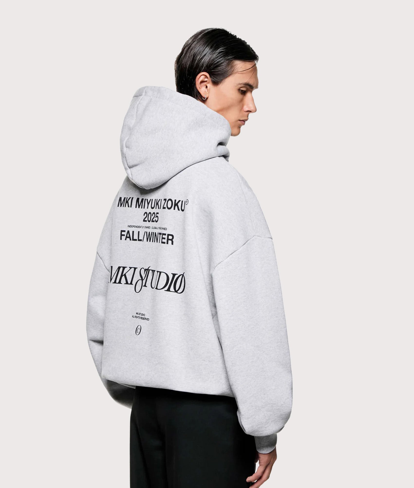 MKI MIYUKI ZOKU Script hoodie in Grey at EQVVS Menswear. Angled model back shot.