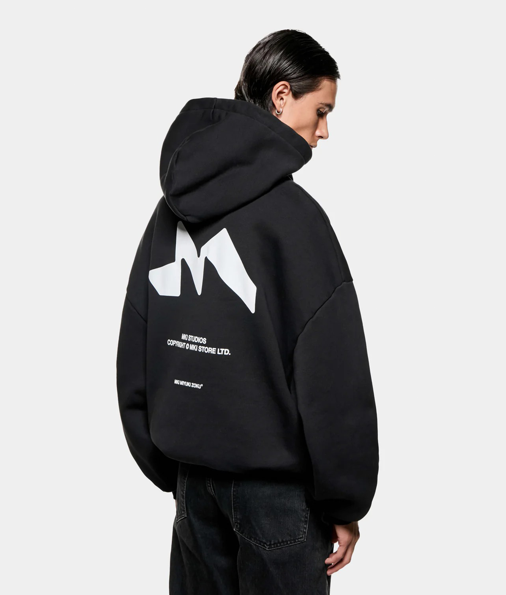 MKI MIYUKI ZOKU Silhouette Hoodie in Black at EQVVS Menswear. Angled back shot. 
