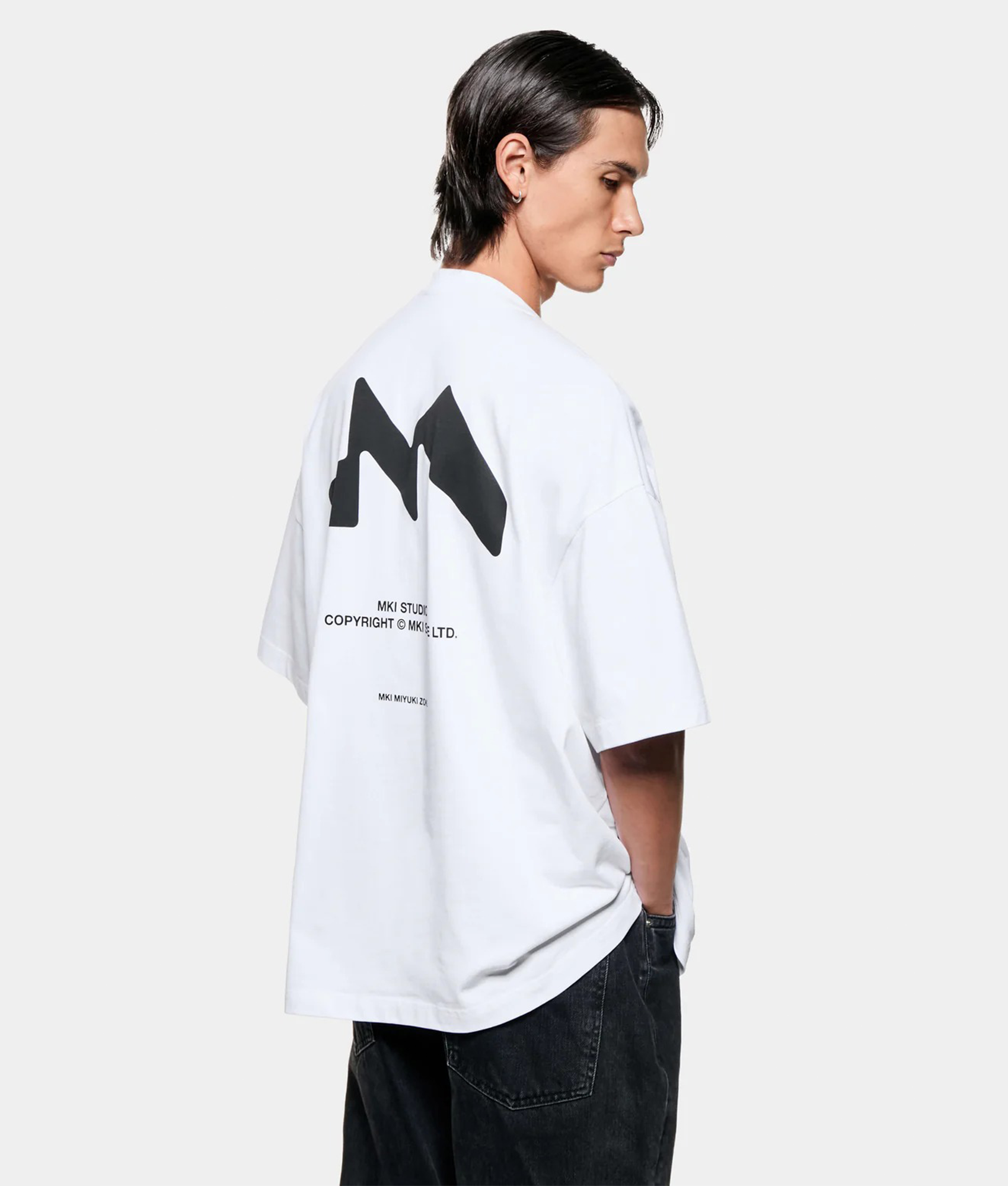 MKI MIYUKI ZOKU Silhouette T-Shirt in White at EQVVS Menswear. Angled model back shot.
