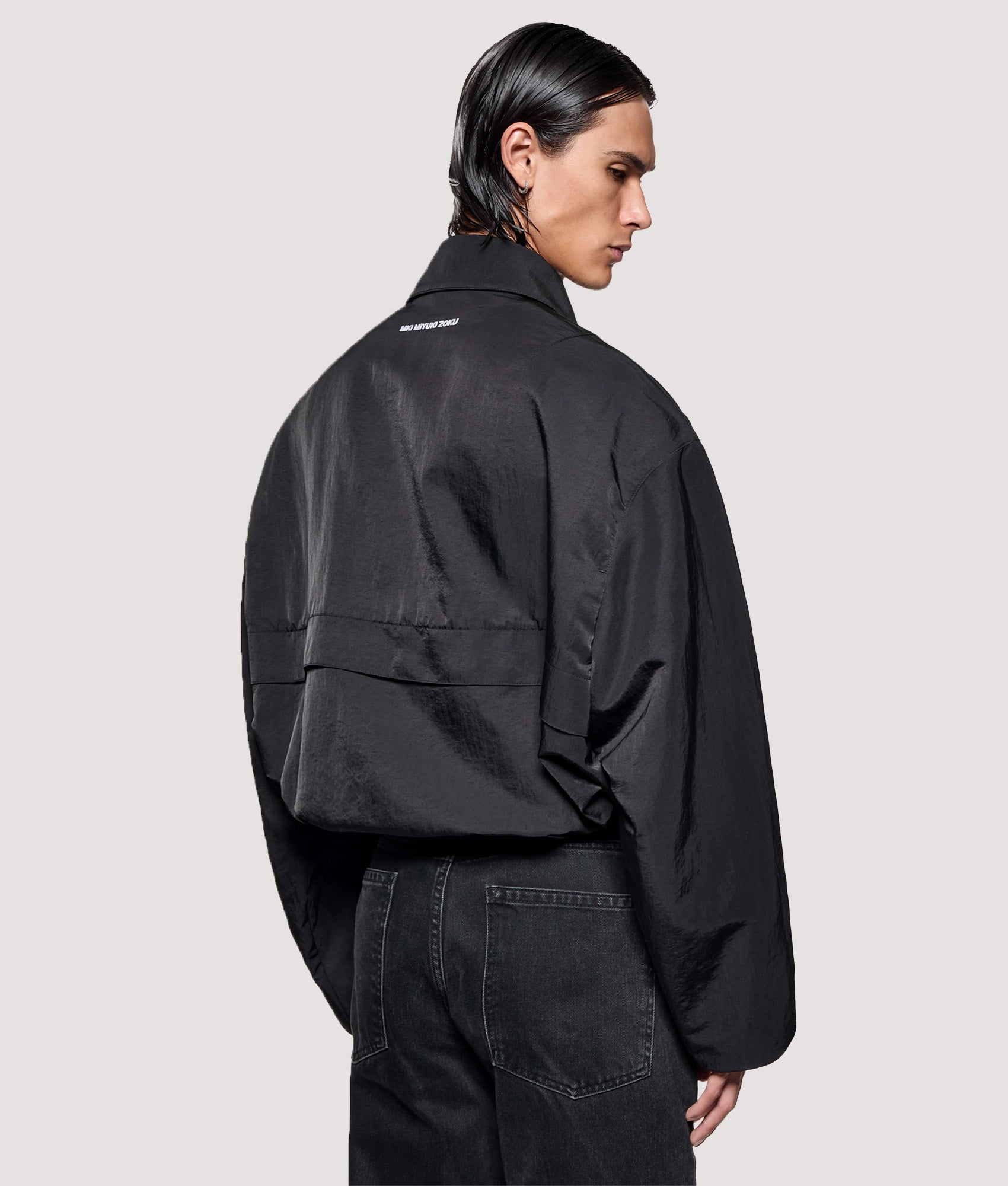 MKI MIYUKI ZOKU Box Fit Silky Nylon Pilot Jacket in Black at EQVVS Menswear. Model back shot.