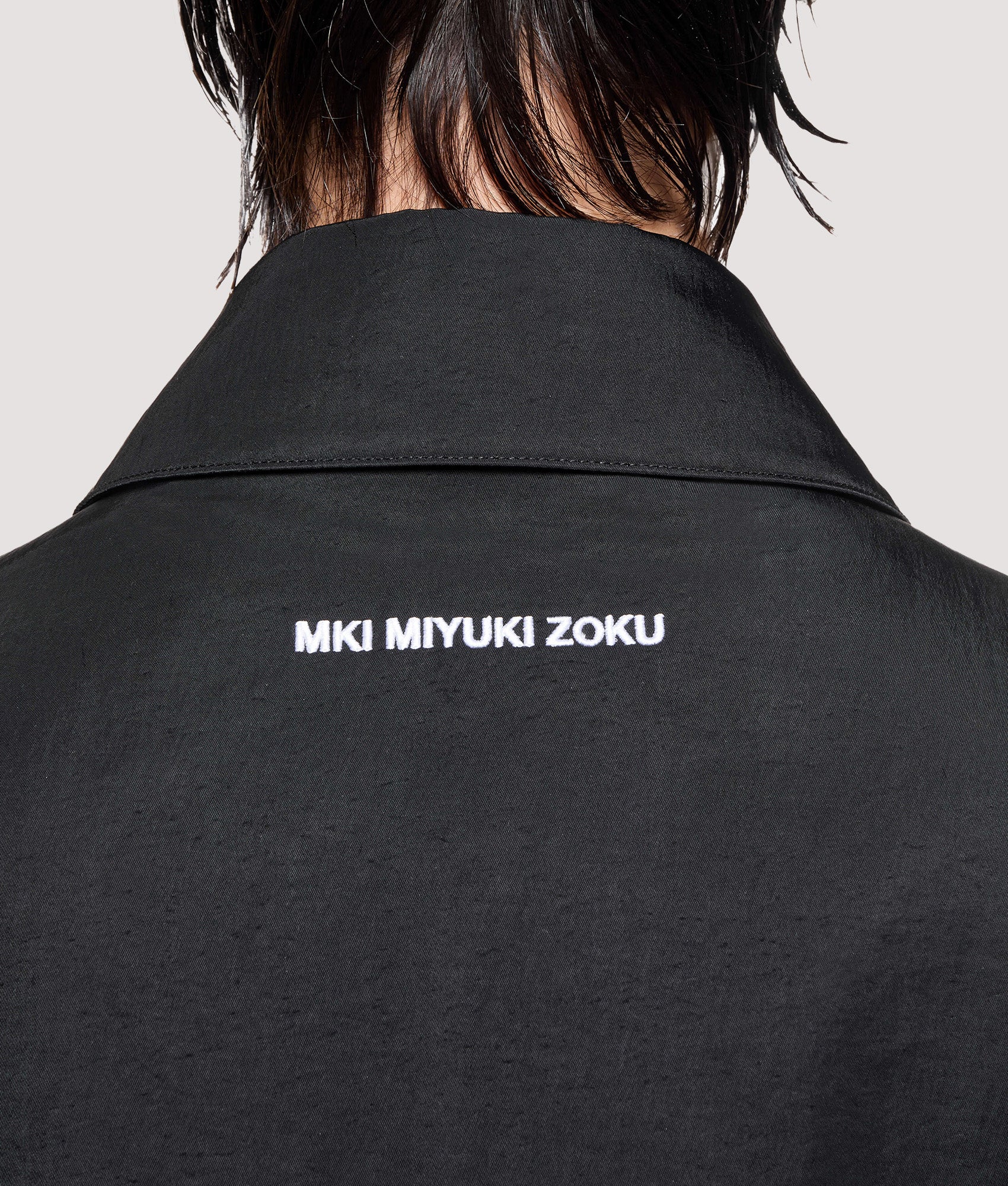 MKI MIYUKI ZOKU Box Fit Silky Nylon Pilot Jacket in Black at EQVVS Menswear. Back detail shot.