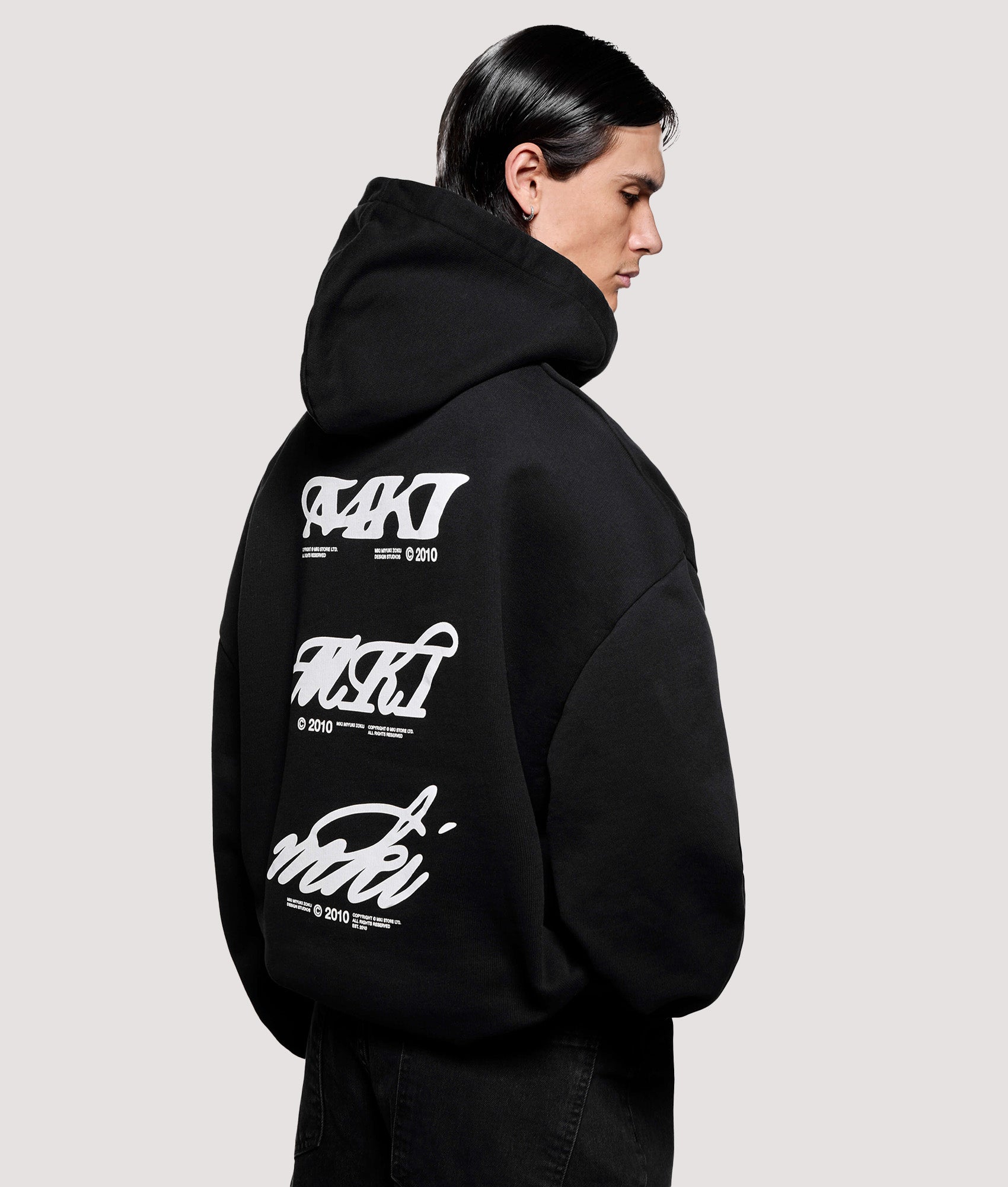 MKI MIYUKI ZOKU Box Fit Stack Hoodie in Black at EQVVS Menswear. Angled model back shot.