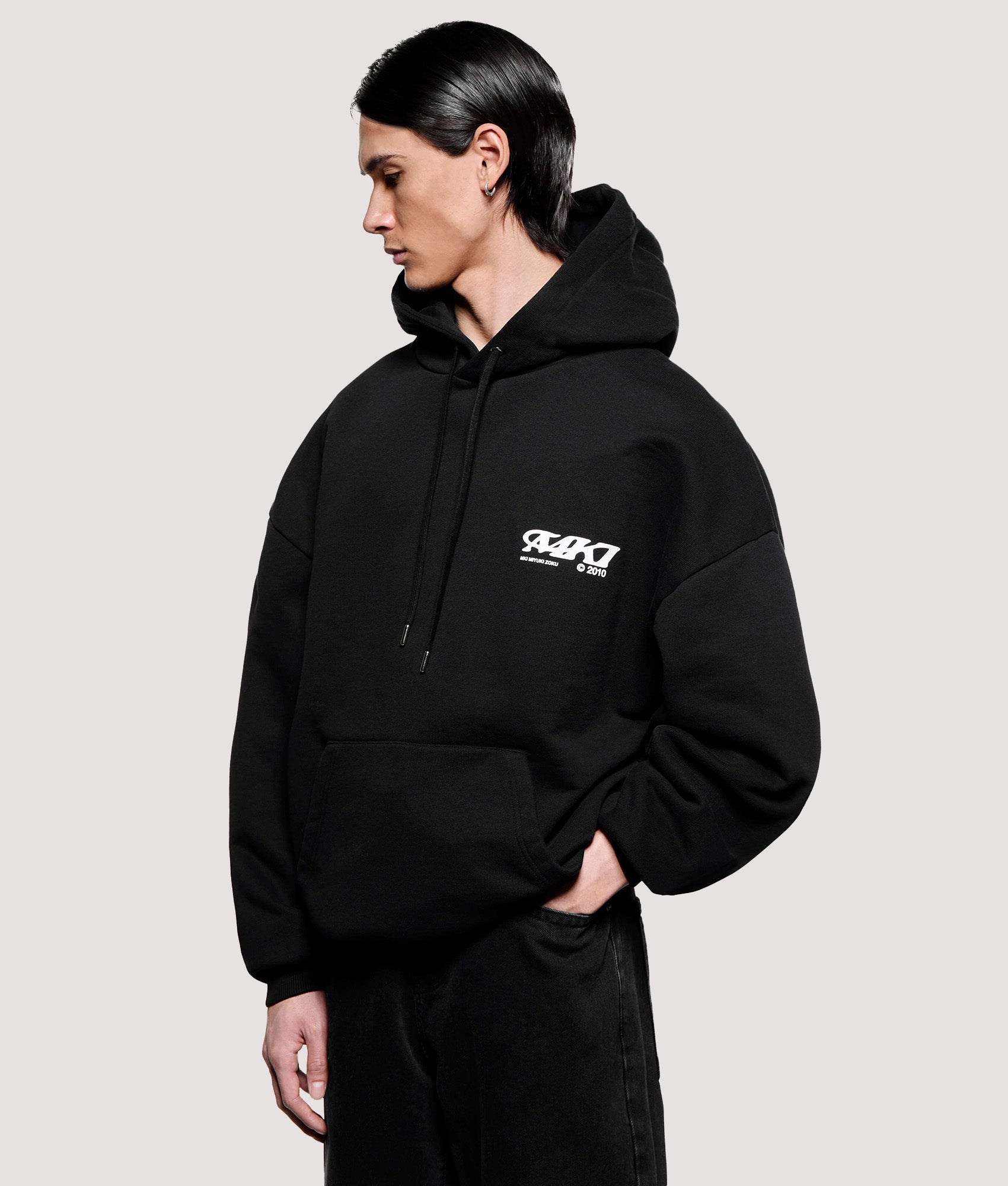 MKI MIYUKI ZOKU Box Fit Stack Hoodie in Black at EQVVS Menswear. Angled model front shot.