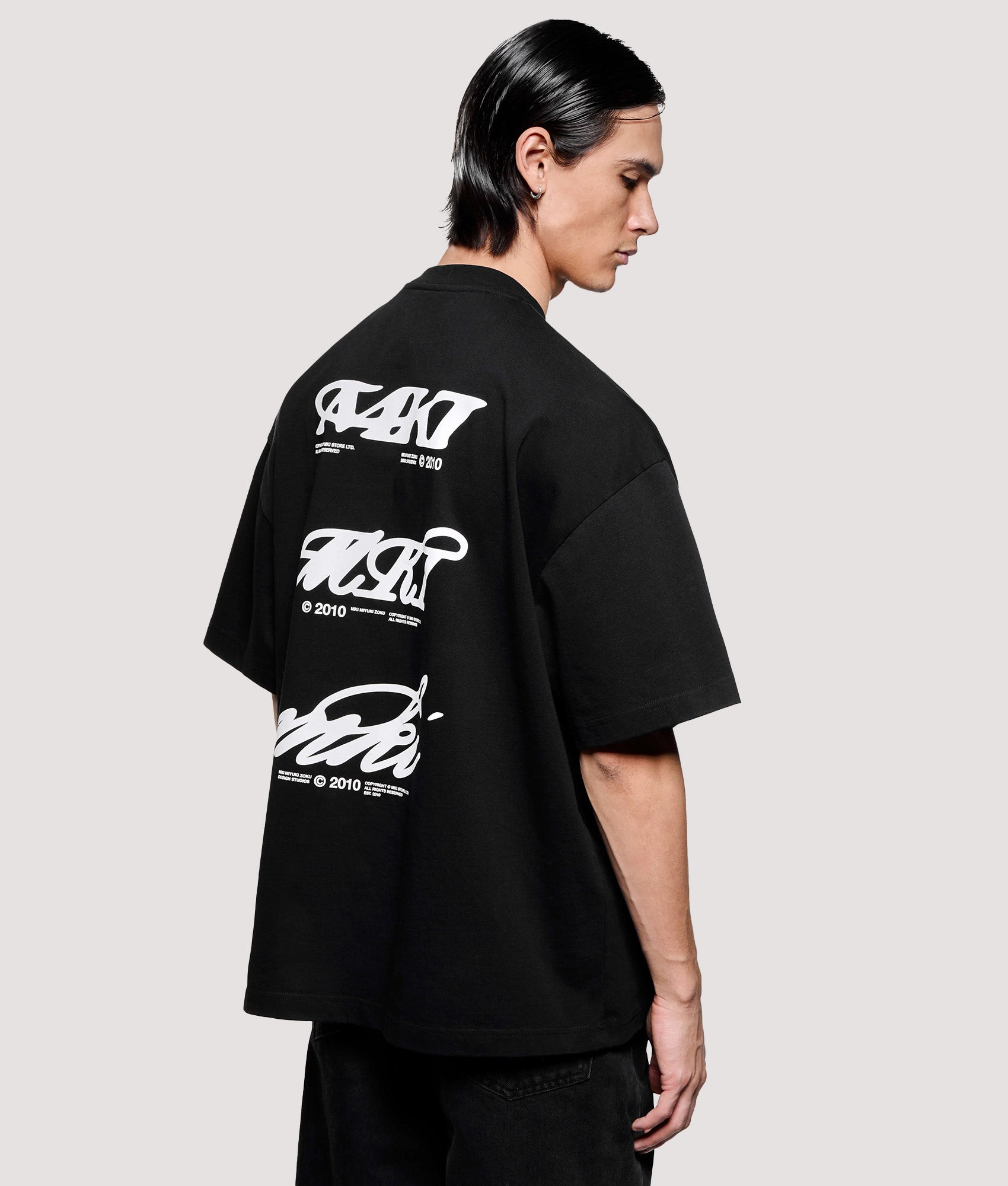 MKI MIYUKI ZOKU Box Fit Flight T-Shirt in Black at EQVVS Menswear. Angled model back shot.