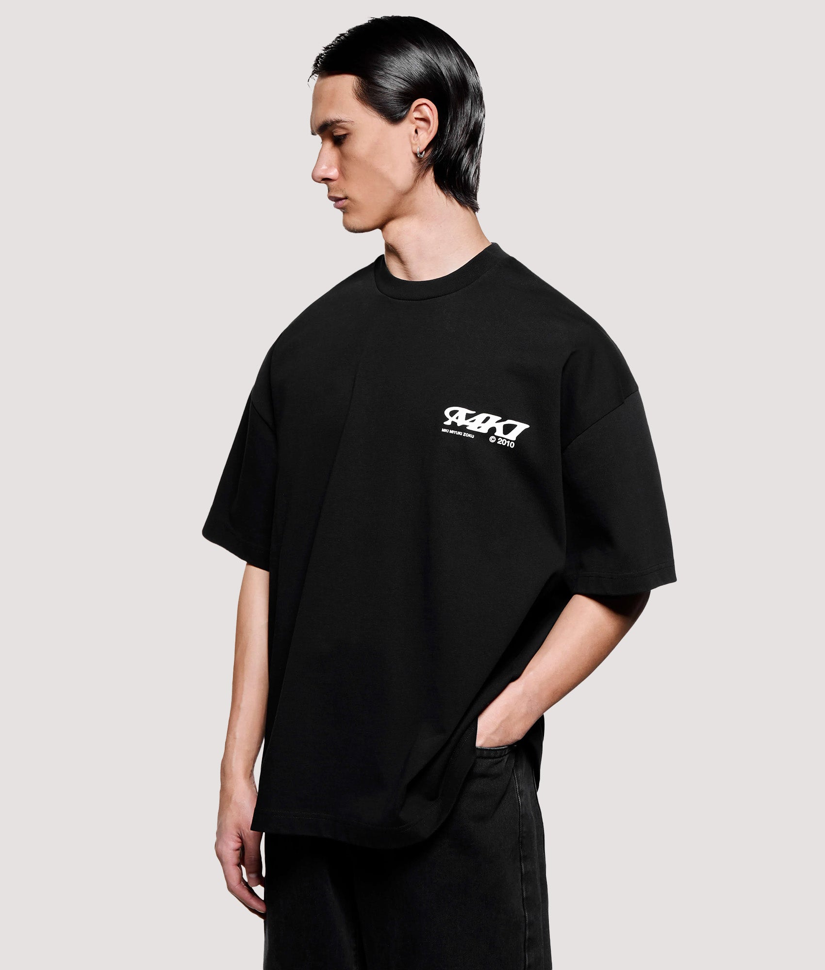 MKI MIYUKI ZOKU Box Fit Flight T-Shirt in Black at EQVVS Menswear. Angled model front shot.