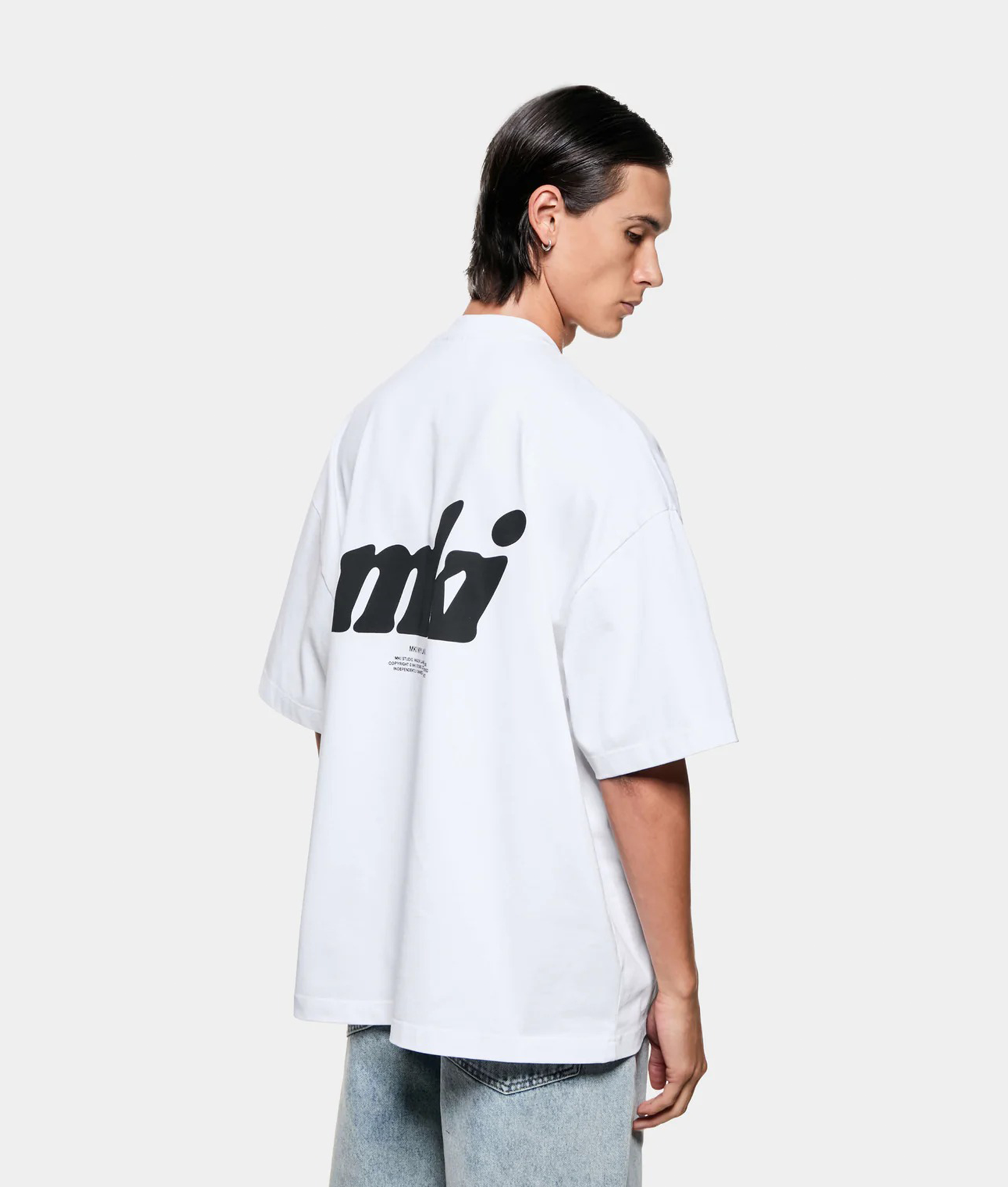 MKI MIYUKI ZOKU Stamp T-Shirt in white at EQVVS Menswear. Angled model back shot.