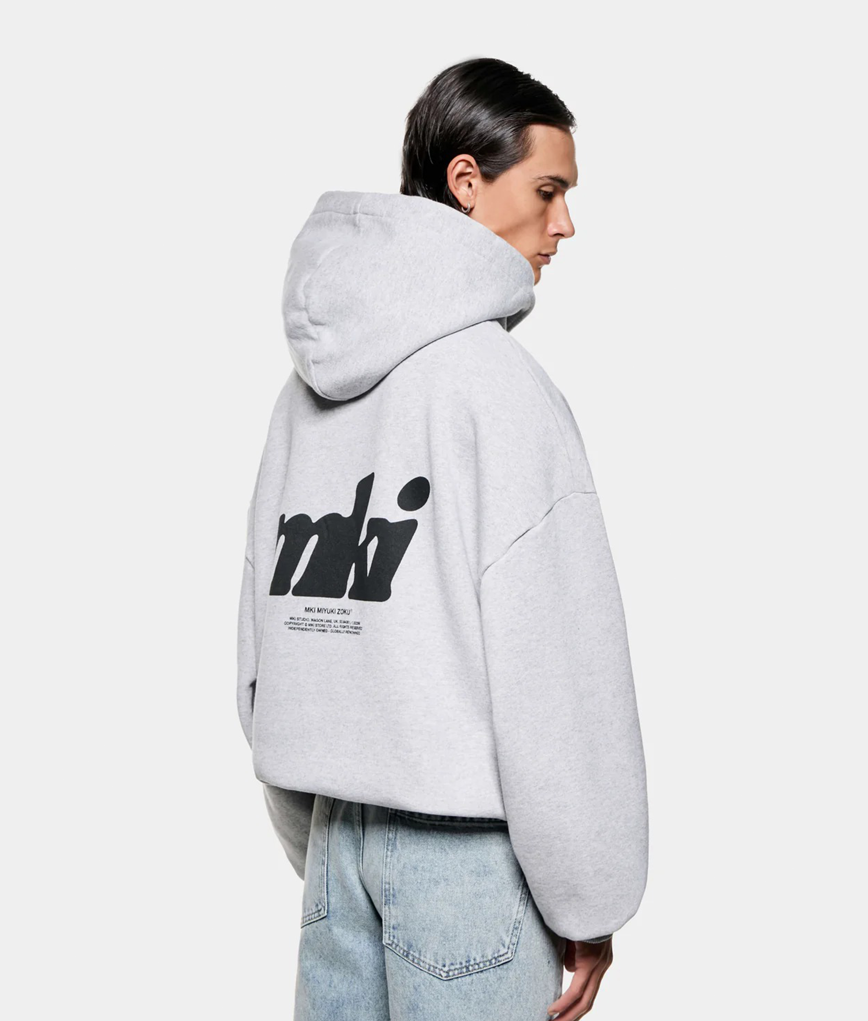 MKI MIYUKI ZOKU Stamp Hoodie in Grey at EQVVS Menswear. Angled model back shot.