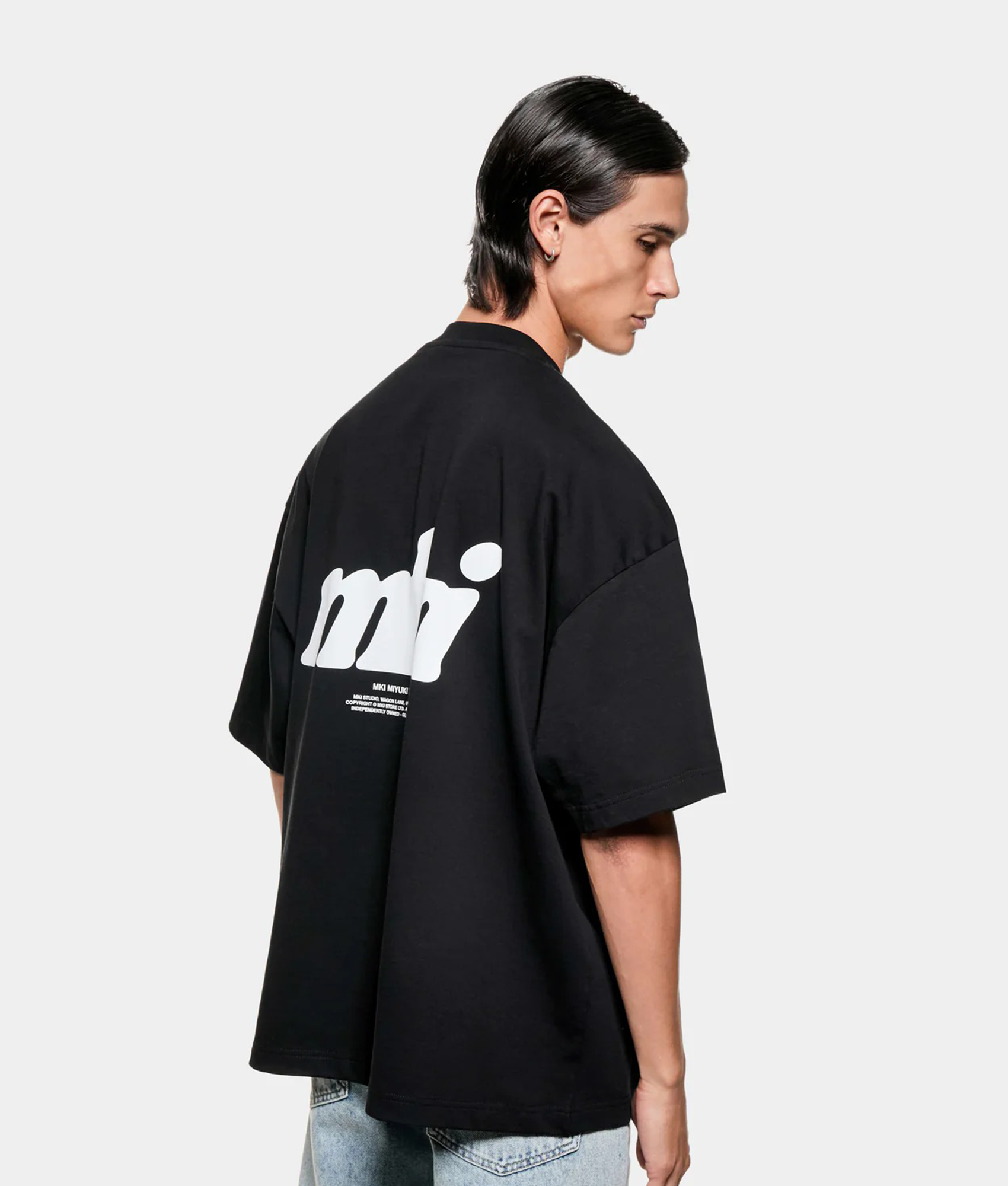 MKI MIYUKI ZOKU Stamp T-Shirt in Black at EQVVS Menswear. Angled model back shot.