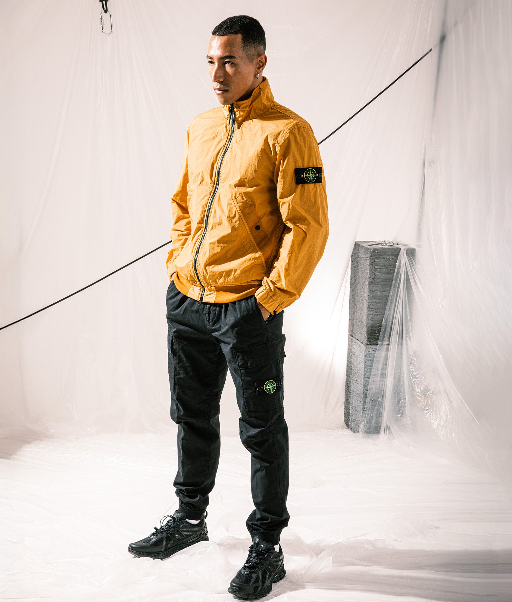 Stone Island Crinkle Reps NY Stand Collar Bomber Jacket in Mustard at EQVVS Menswear. Campaign shot.