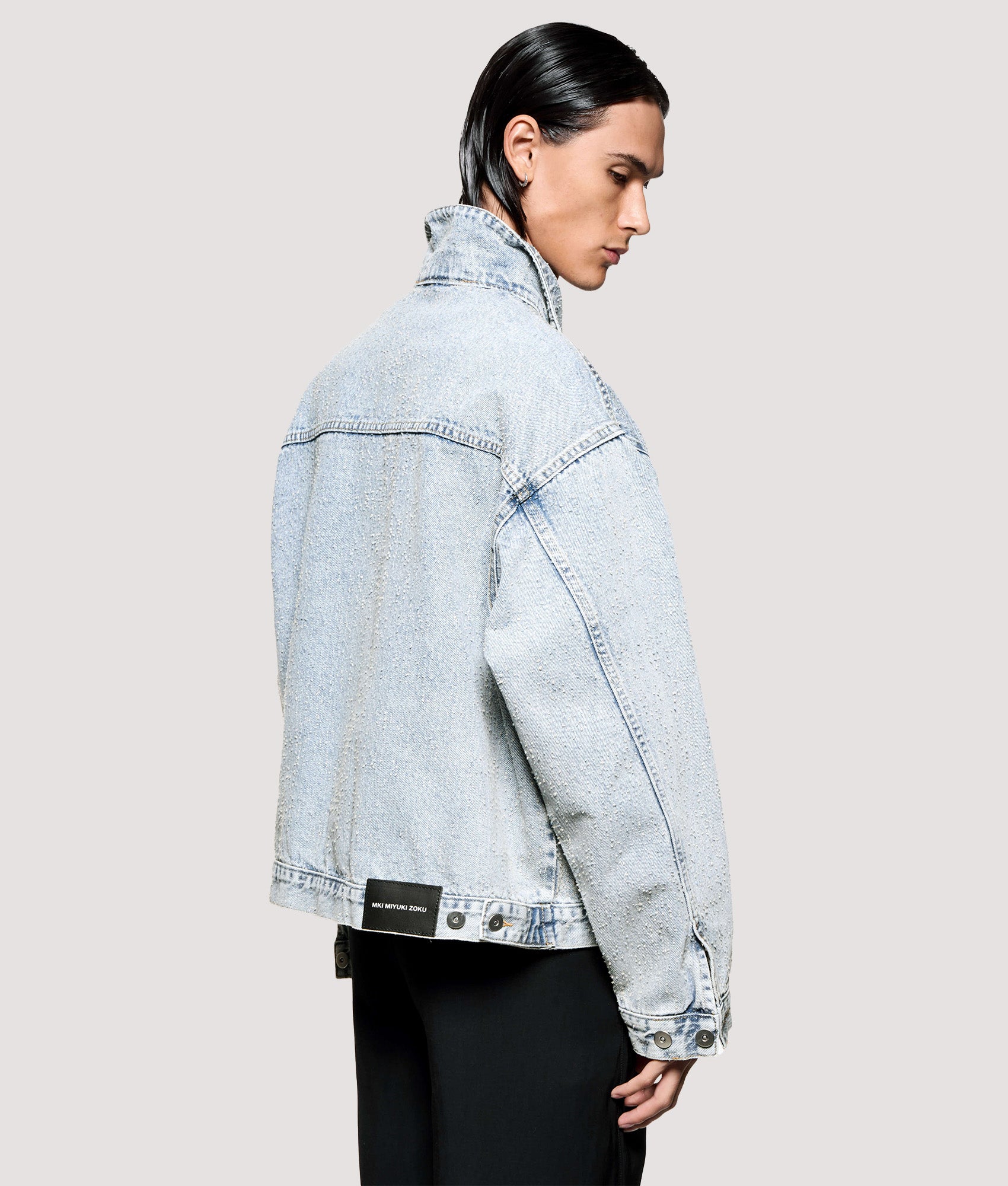 MKI MIYUKI ZOKU Box Fit Twisted Weave Trucker Jacket in Bleach Wash at EQVVS Menswear. Angled model back shot.