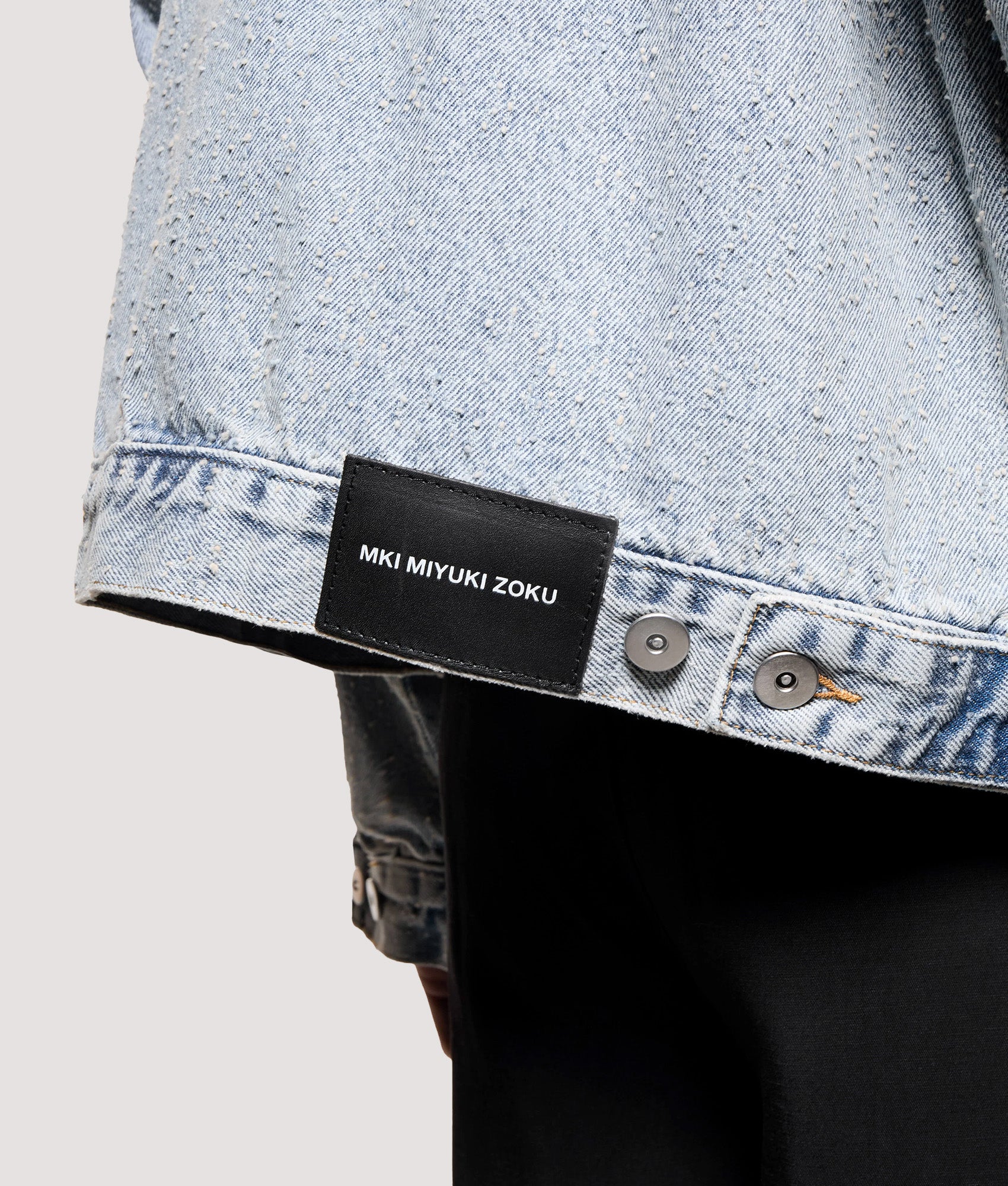 MKI MIYUKI ZOKU Box Fit Twisted Weave Trucker Jacket in Bleach Wash at EQVVS Menswear. Back detail shot.