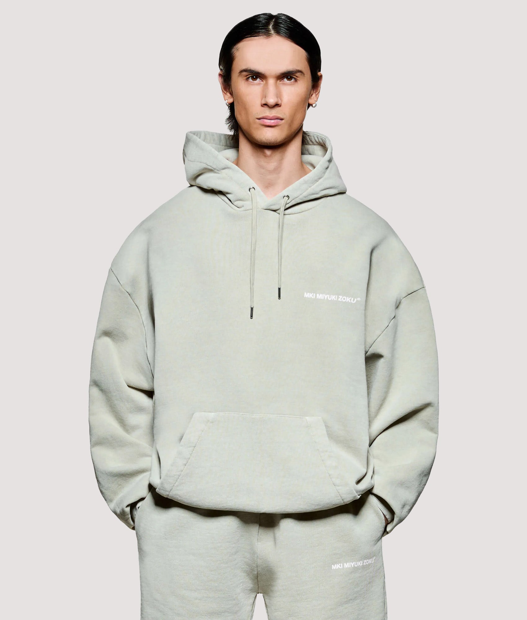 MKI MIYUKI ZOKU Box Fit Uniform Hoodie in Pigment Cement at EQVVS Menswear. Model front shot.