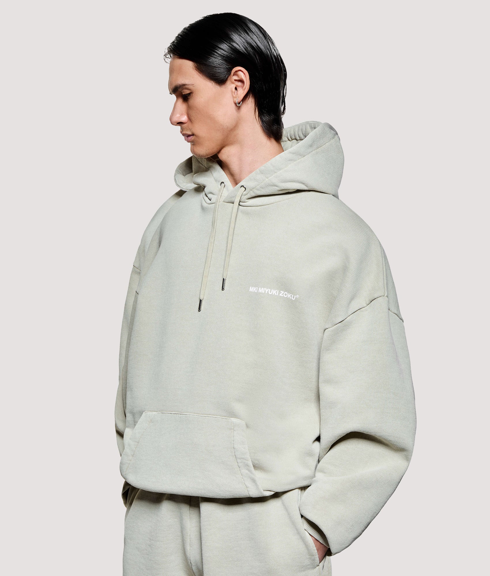 MKI MIYUKI ZOKU Box Fit Uniform Hoodie in Pigment Cement at EQVVS Menswear. Model front shot.