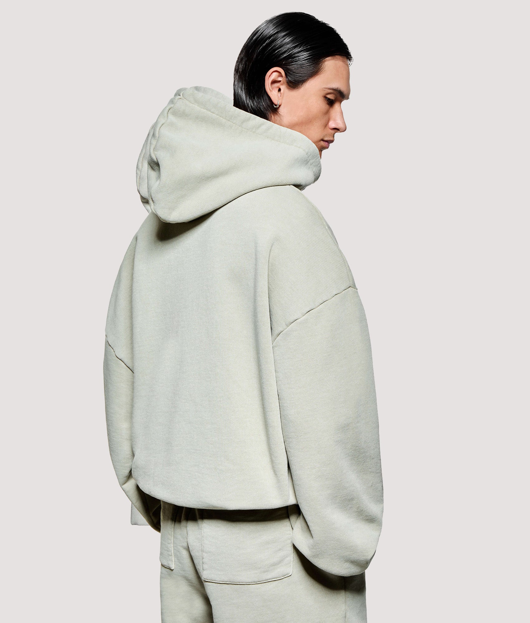 MKI MIYUKI ZOKU Box Fit Uniform Hoodie in Pigment Cement at EQVVS Menswear. Model back shot.