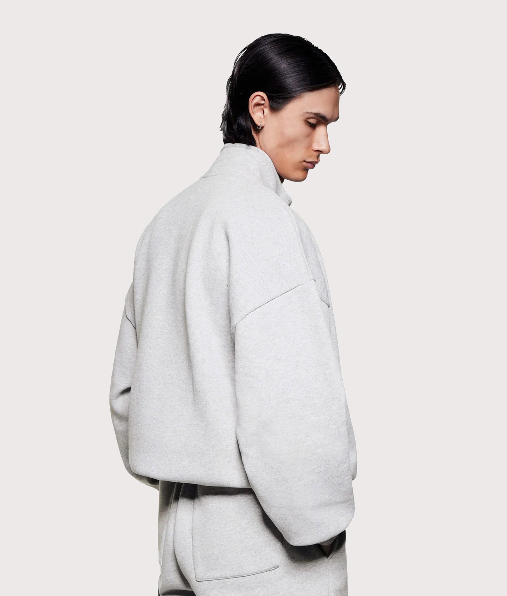 MKI MIYUKI ZOKU Oversized Uniform Quarter Zip Sweatshirt in Grey at EQVVS Menswear. Angled model back shot. 