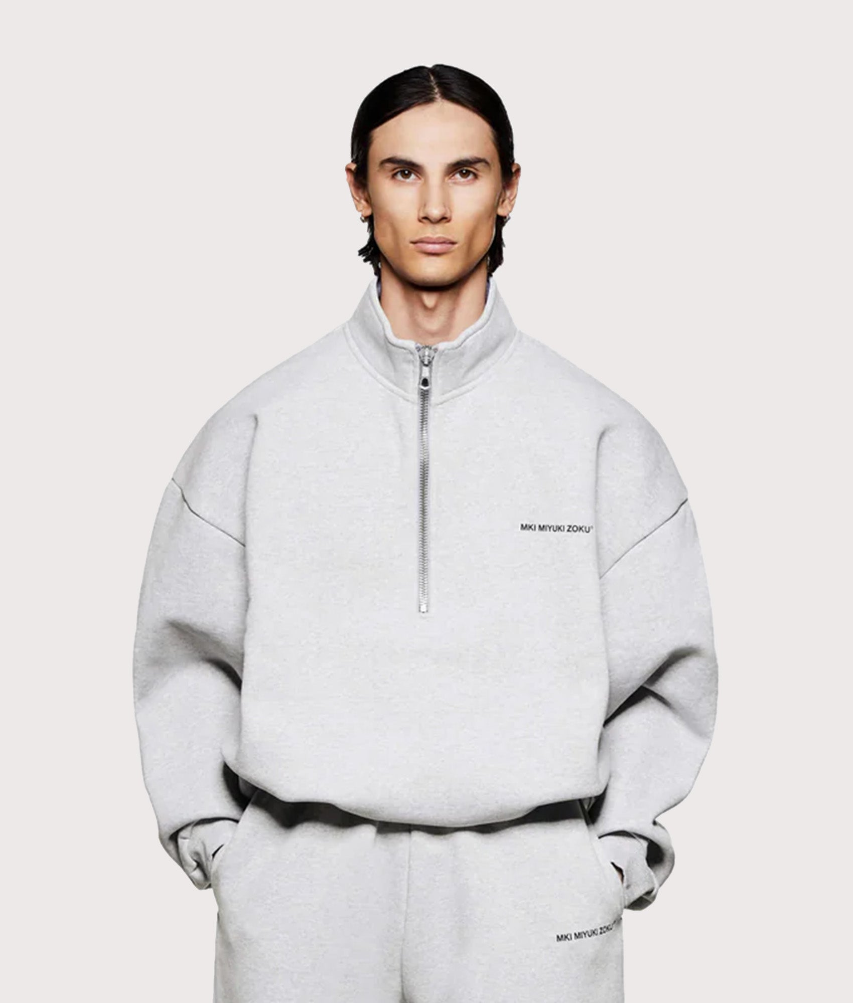 MKI MIYUKI ZOKU Oversized Uniform Quarter Zip Sweatshirt in Grey at EQVVS Menswear. Model front shot.