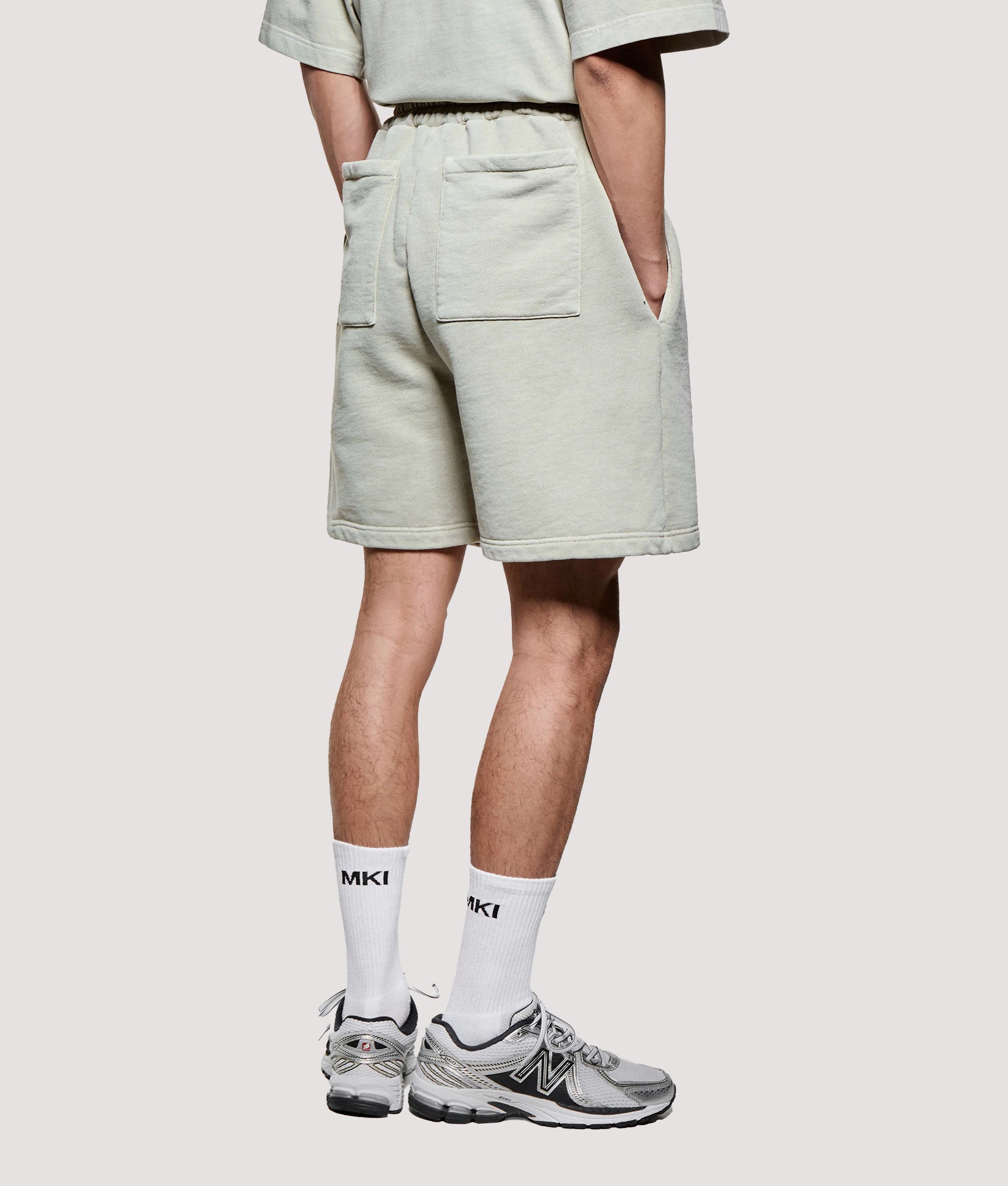 MKI MIYUKI ZOKU Relaxed Fit Uniform Shorts in Pigment Cement at EQVVS Menswear. Angled model back shot.