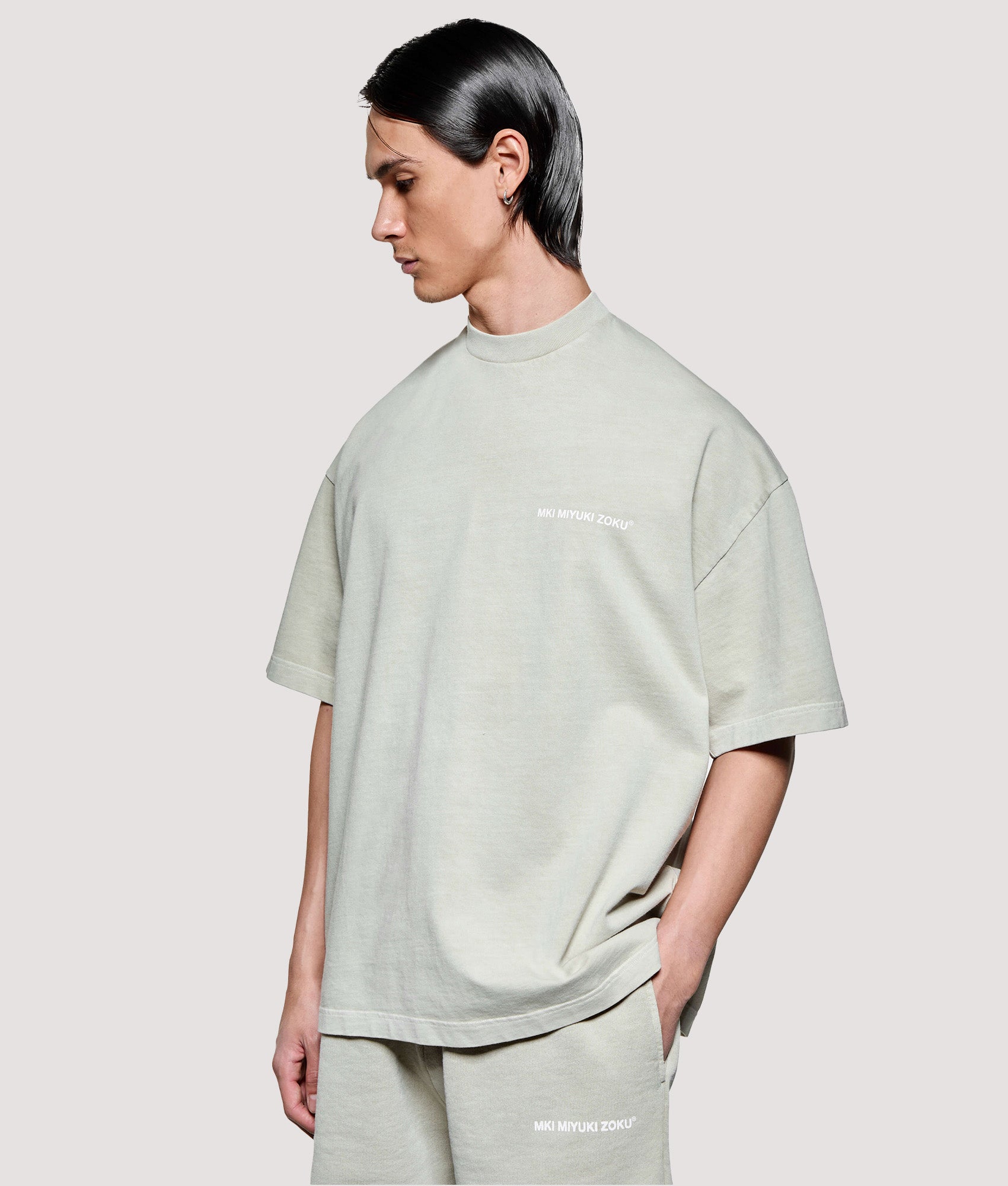 MKI MIYUKI ZOKU Box Fit Uniform T-Shirt in Pigment Cement at EQVVS Menswear. Model angled front shot.
