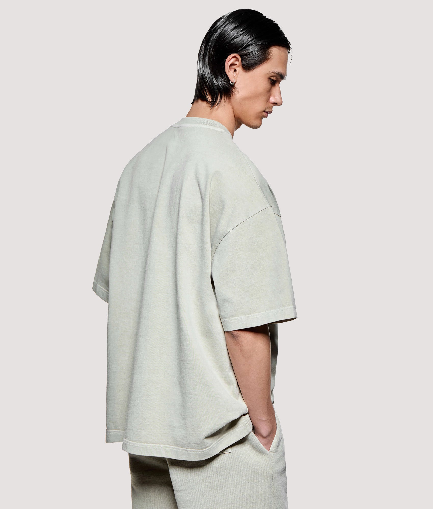 MKI MIYUKI ZOKU Box Fit Uniform T-Shirt in Pigment Cement at EQVVS Menswear. Model back shot.
