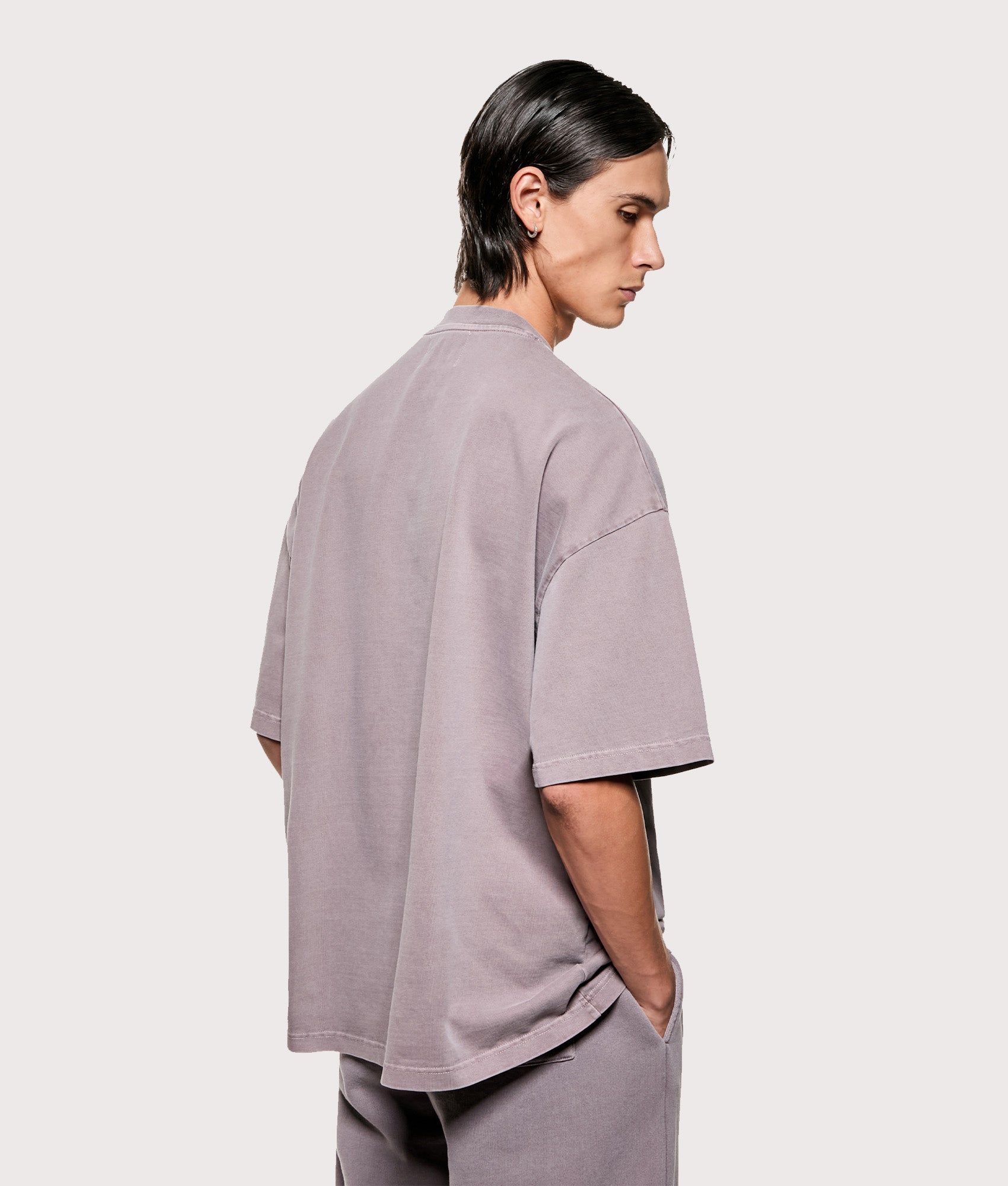 MKI MIYUKI ZOKU Oversized Uniform T-Shirt in Pigment Raisin at EQVVS Menswear. Angled model back shot.