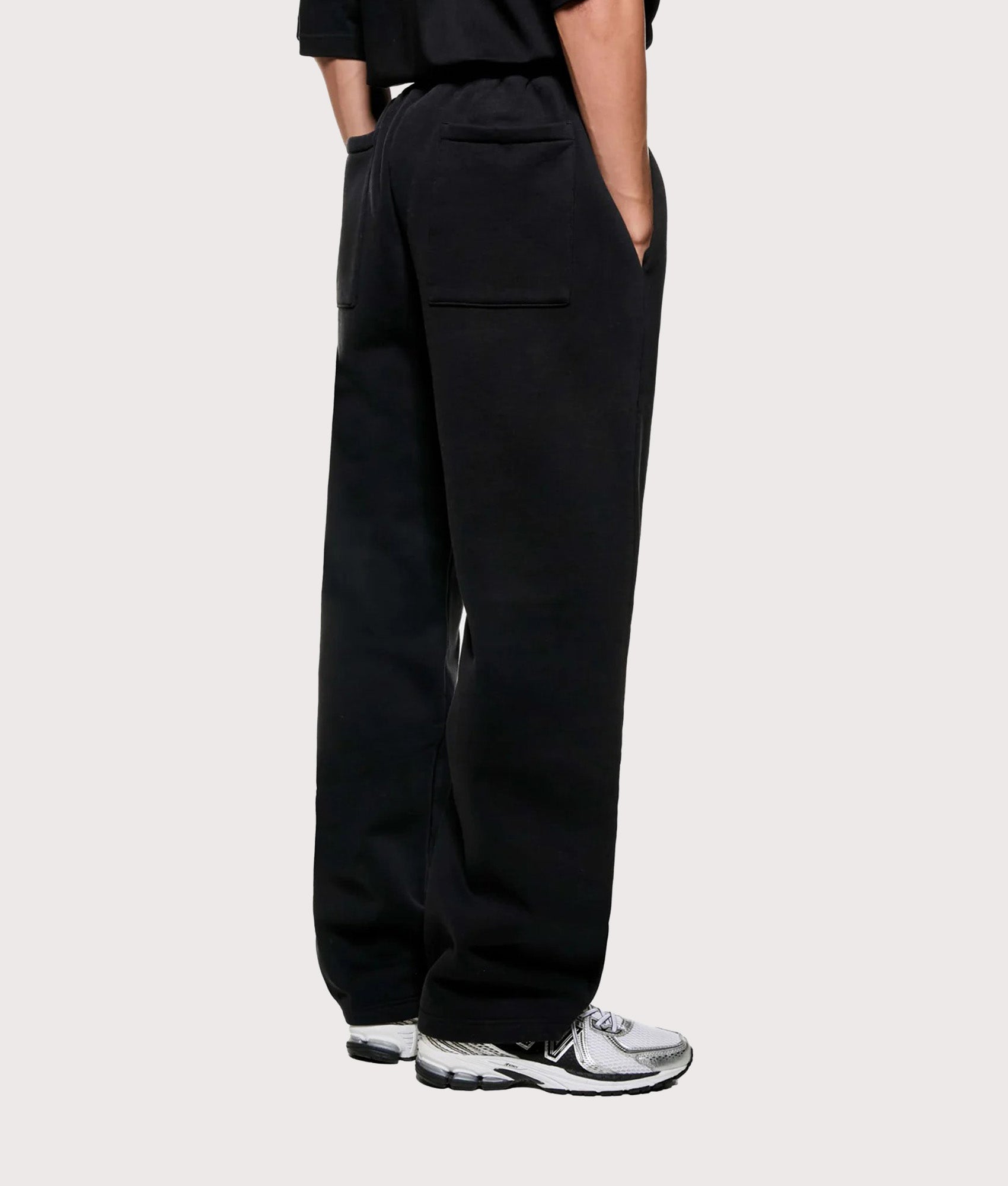 MKI MIYUKI ZOKU Uniform Wide Leg Joggers in Black at EQVVS Menswear. Angled model back shot.