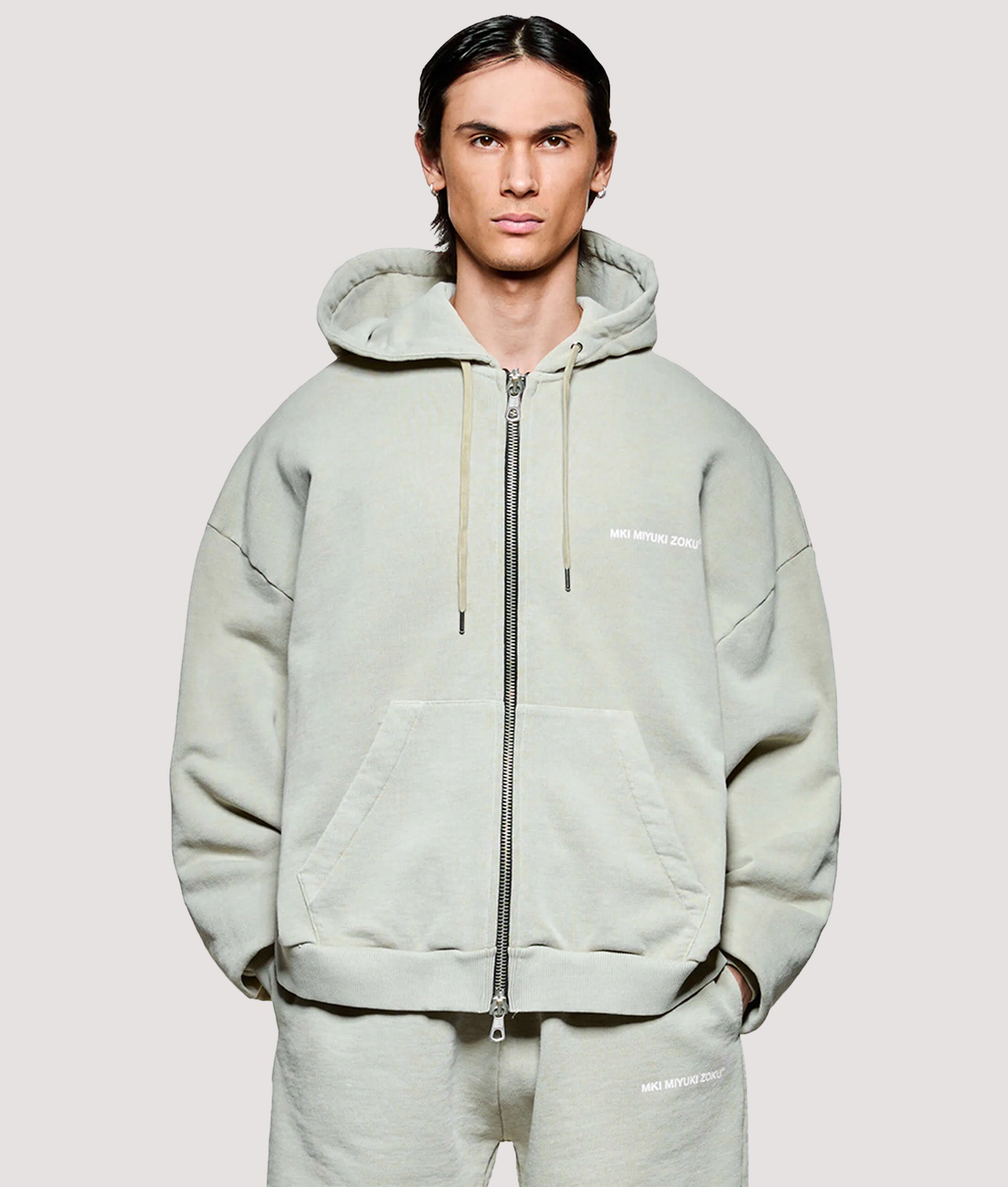 MKI MIYUKI ZOKU Box Fit Uniform Zip Through Hoodie in Pigment Cement at EQVVS Menswear. Model front shot.