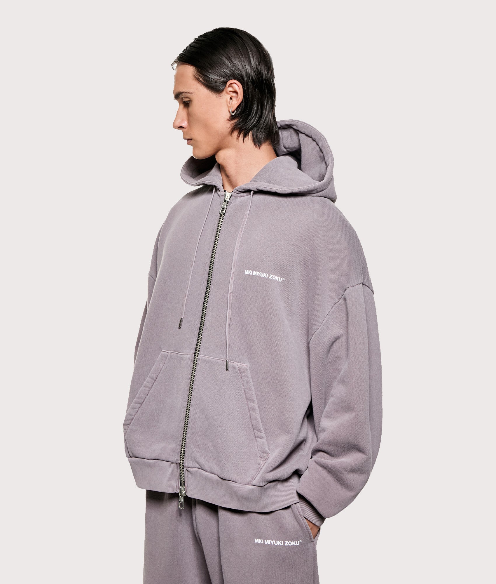 MKI MIYUKI ZOKU Uniform Zip Through Hoodie in Pigment Raisin at EQVVS Menswear. Angled model front shot.