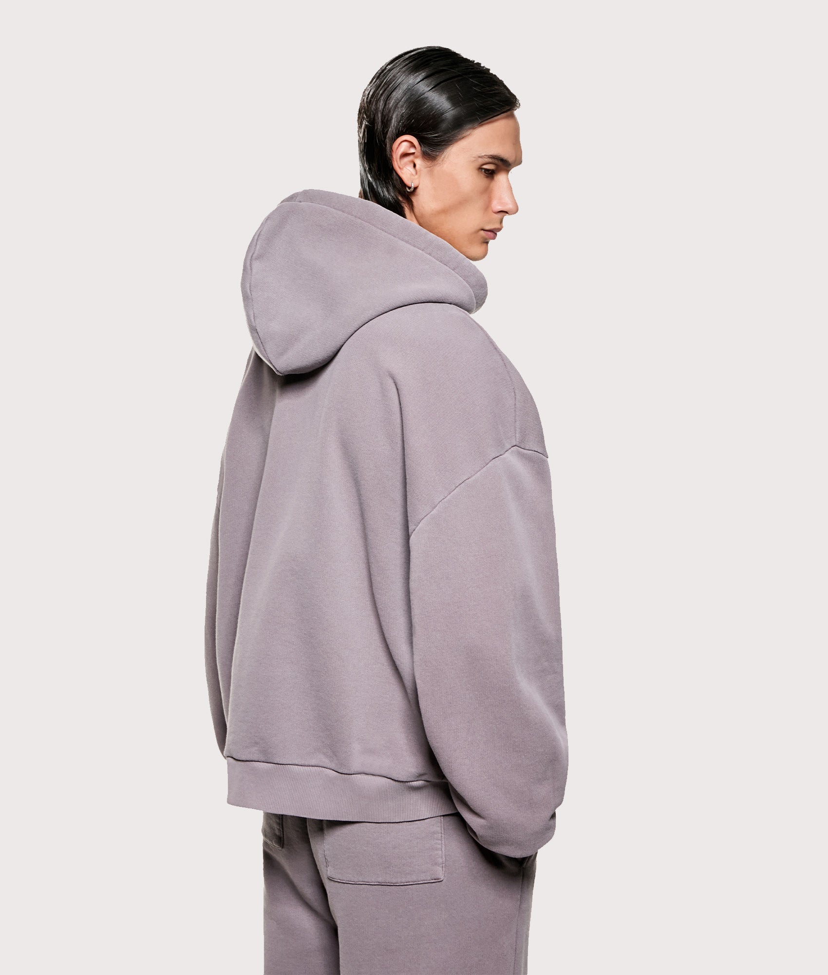MKI MIYUKI ZOKU Uniform Zip Through Hoodie in Pigment Raisin at EQVVS Menswear. Angled model back shot.