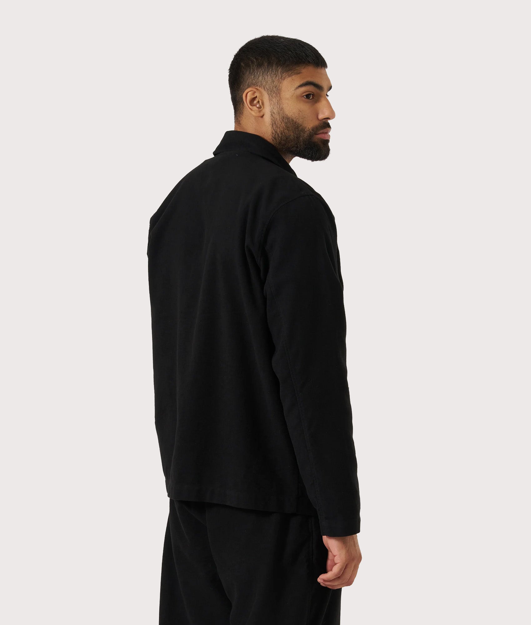 Universal Works Comfort Moleskin Field Jacket in Black at EQVVS Menswear. Model back shot.