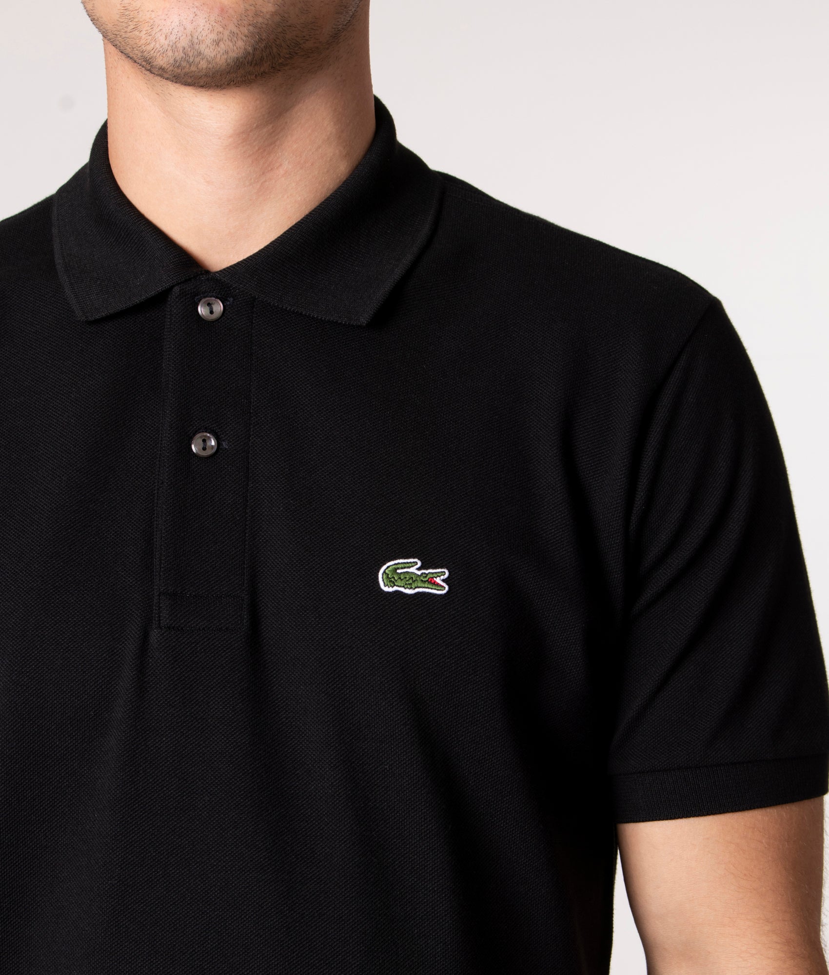 Lacoste Classic Fit L1212 Croc Logo Polo Shirt in Black at EQVVS Menswear. Detail shot.